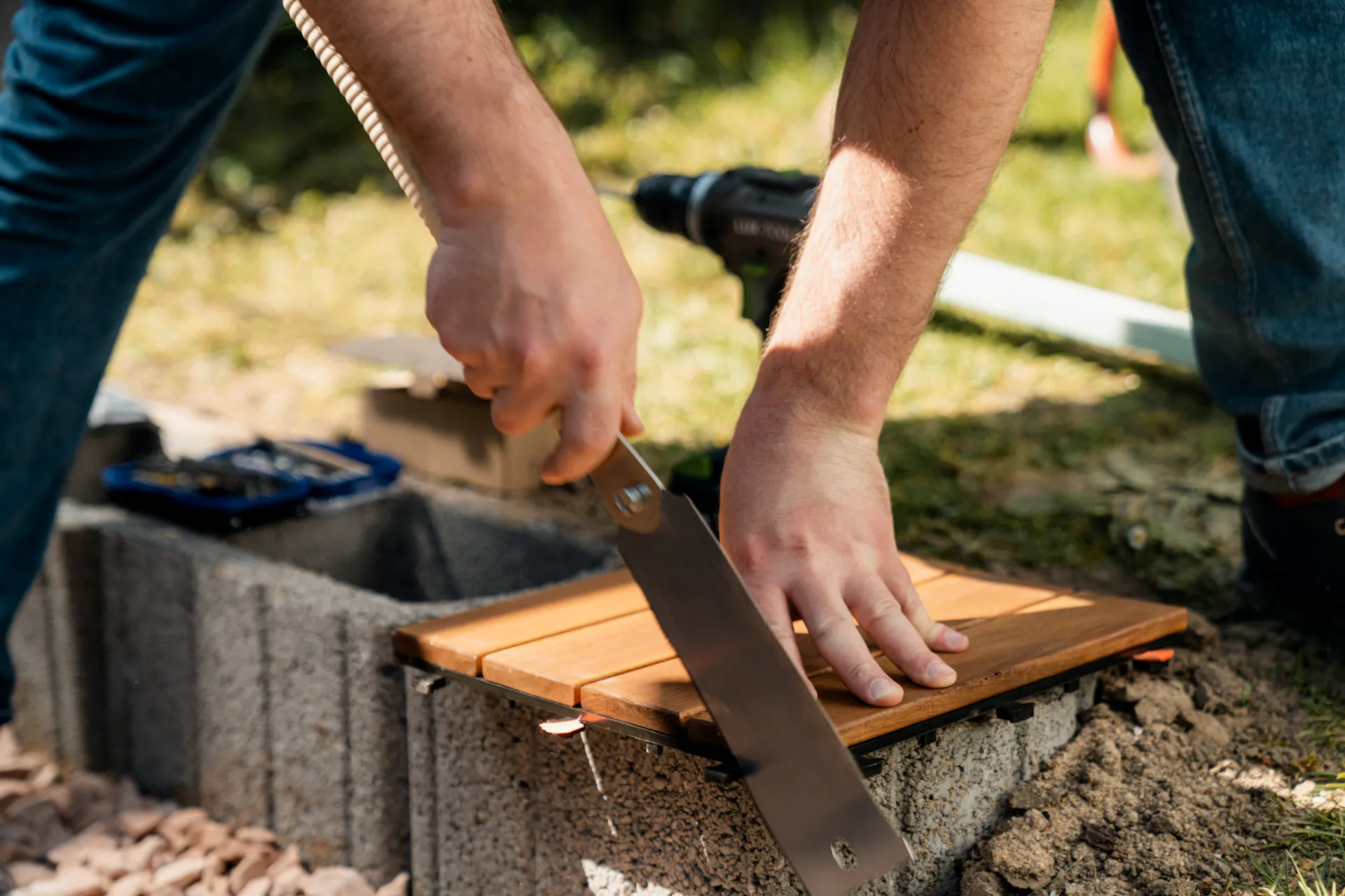 La persona elimina la plastica in eccesso da una piastrella a clic con una sega giapponese.