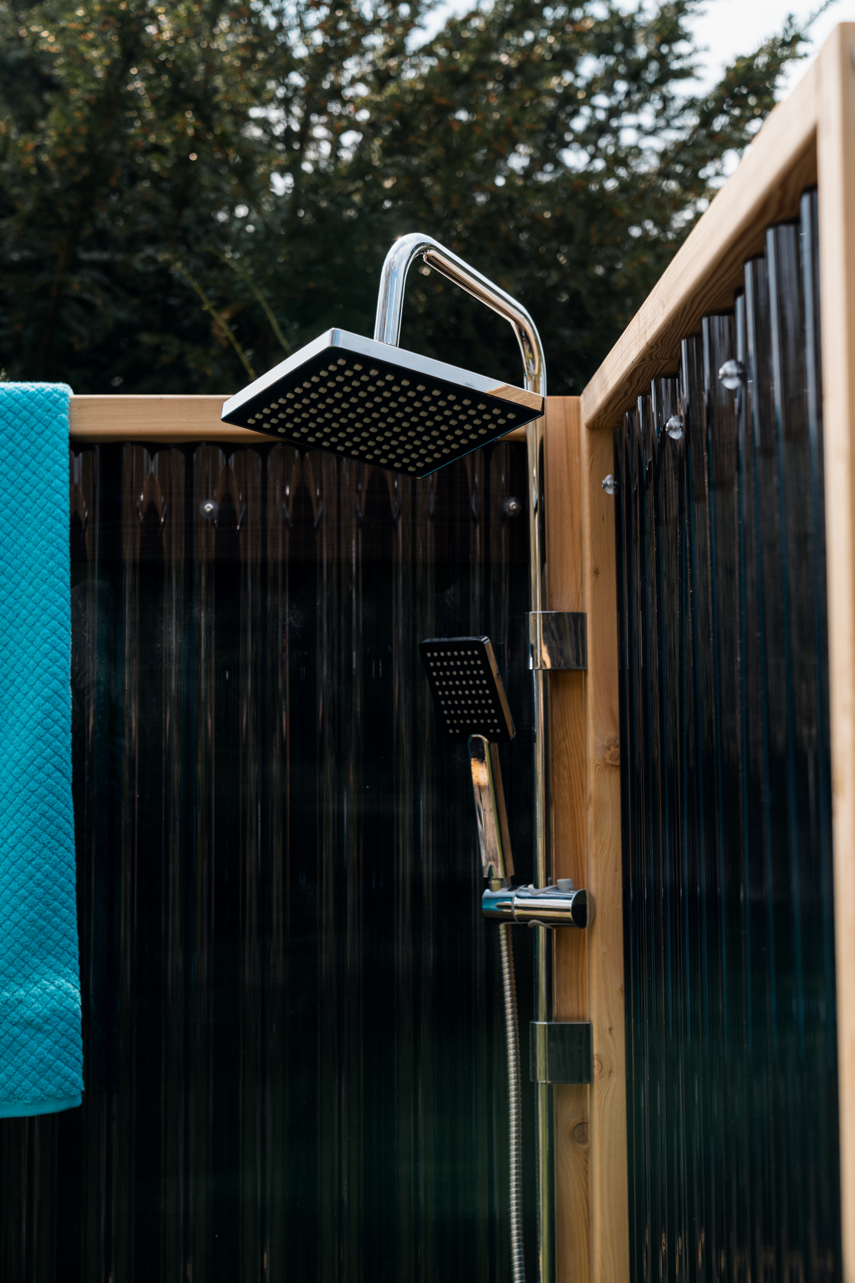 Gartendusche mit Sichtschutzwand, Duscharmatur und Handtuch im Garten