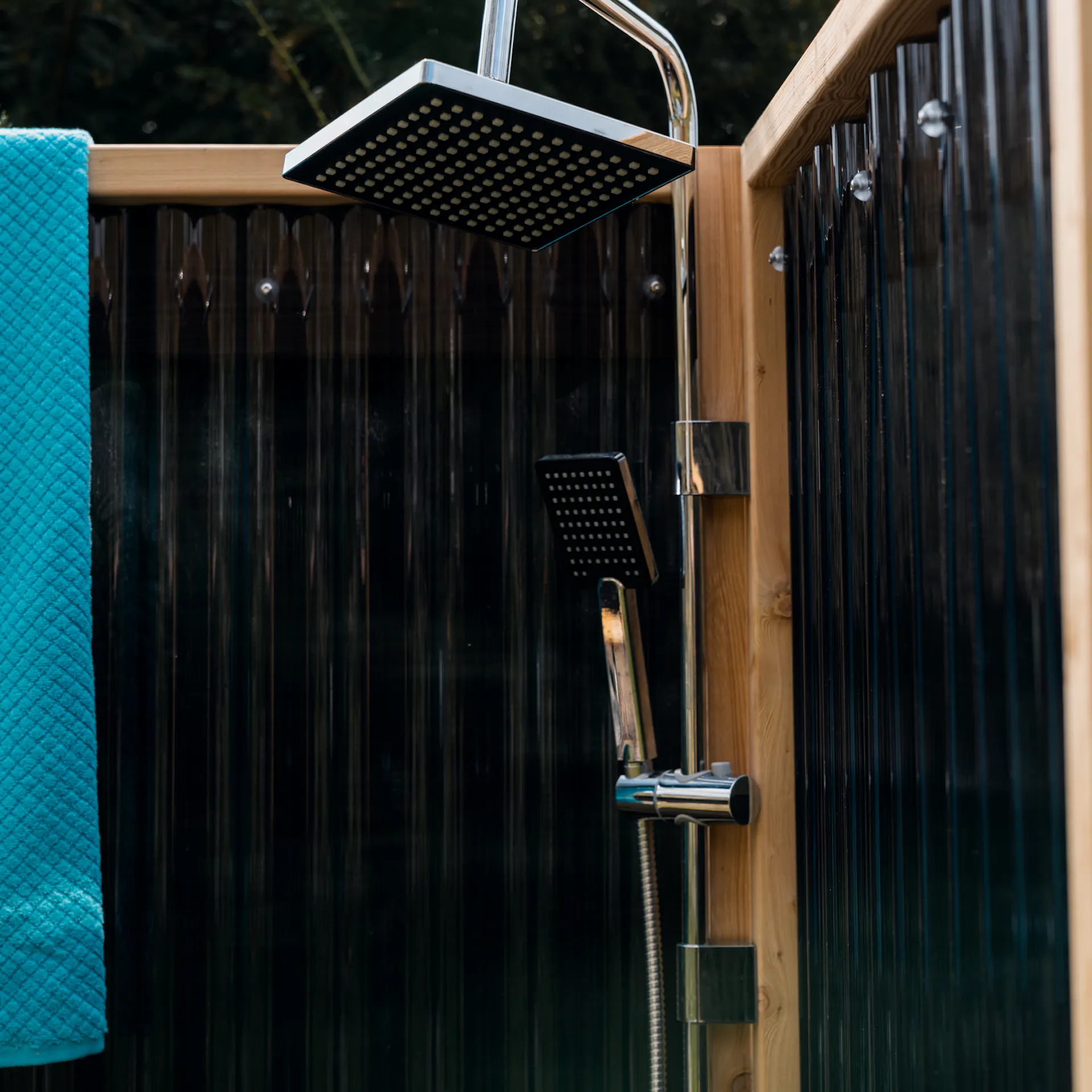 Gartendusche mit Sichtschutzwand, Duscharmatur und Handtuch im Garten