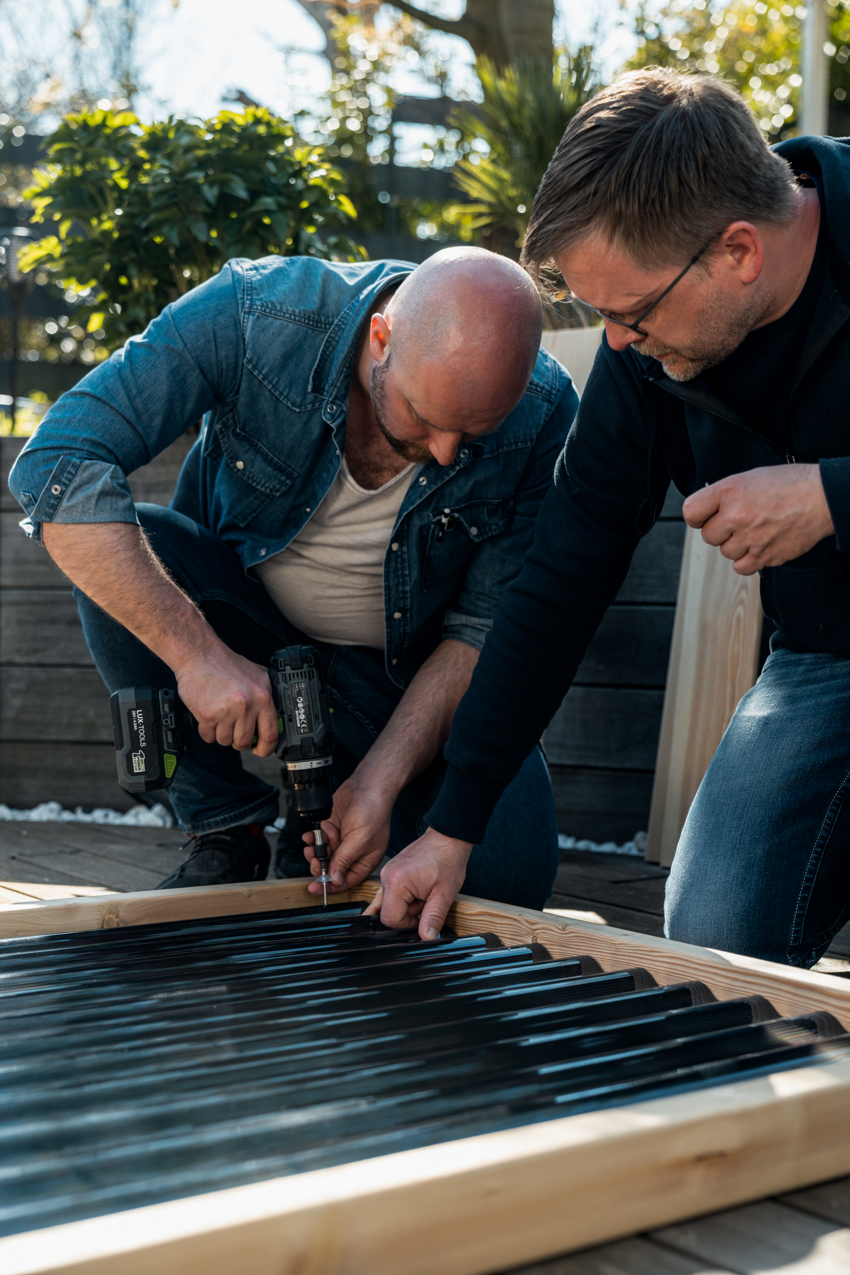 Due persone avvitano i pannelli ondulati al telaio