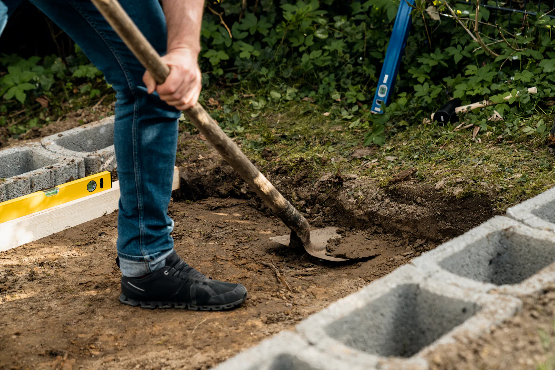 Con una pala, l’amante del fai da te rimuove 20 cm di terriccio in giardino.