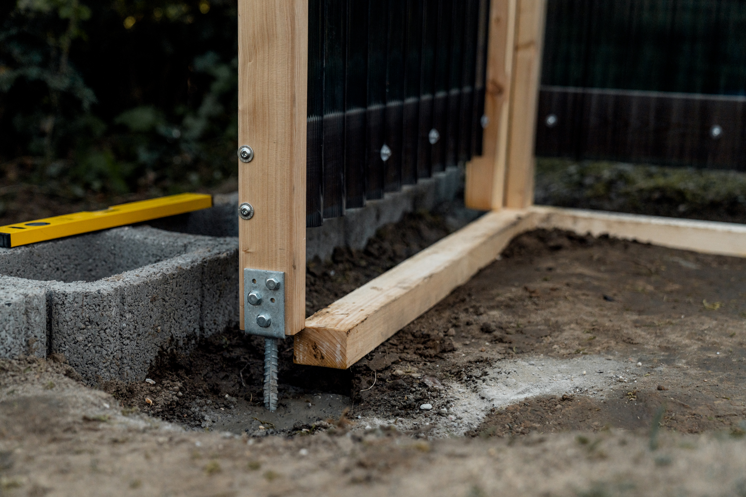 Il palo di legno nella basetta di appoggio è posizionato nelle fondamenta riempite di calcestruzzo rapido in giardino.