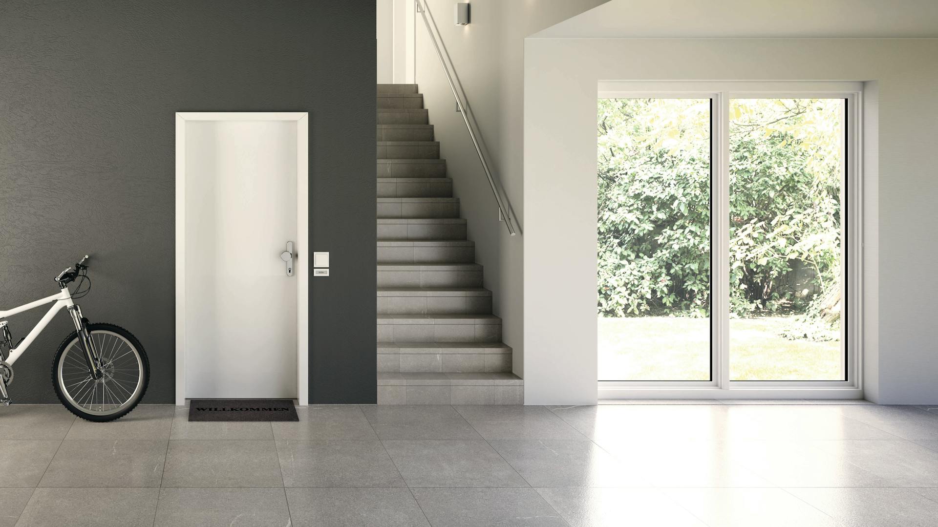 Innenraum eines gefliesten Innenbereichs mit bodentiefen Fenstern und einer weißen Tür.