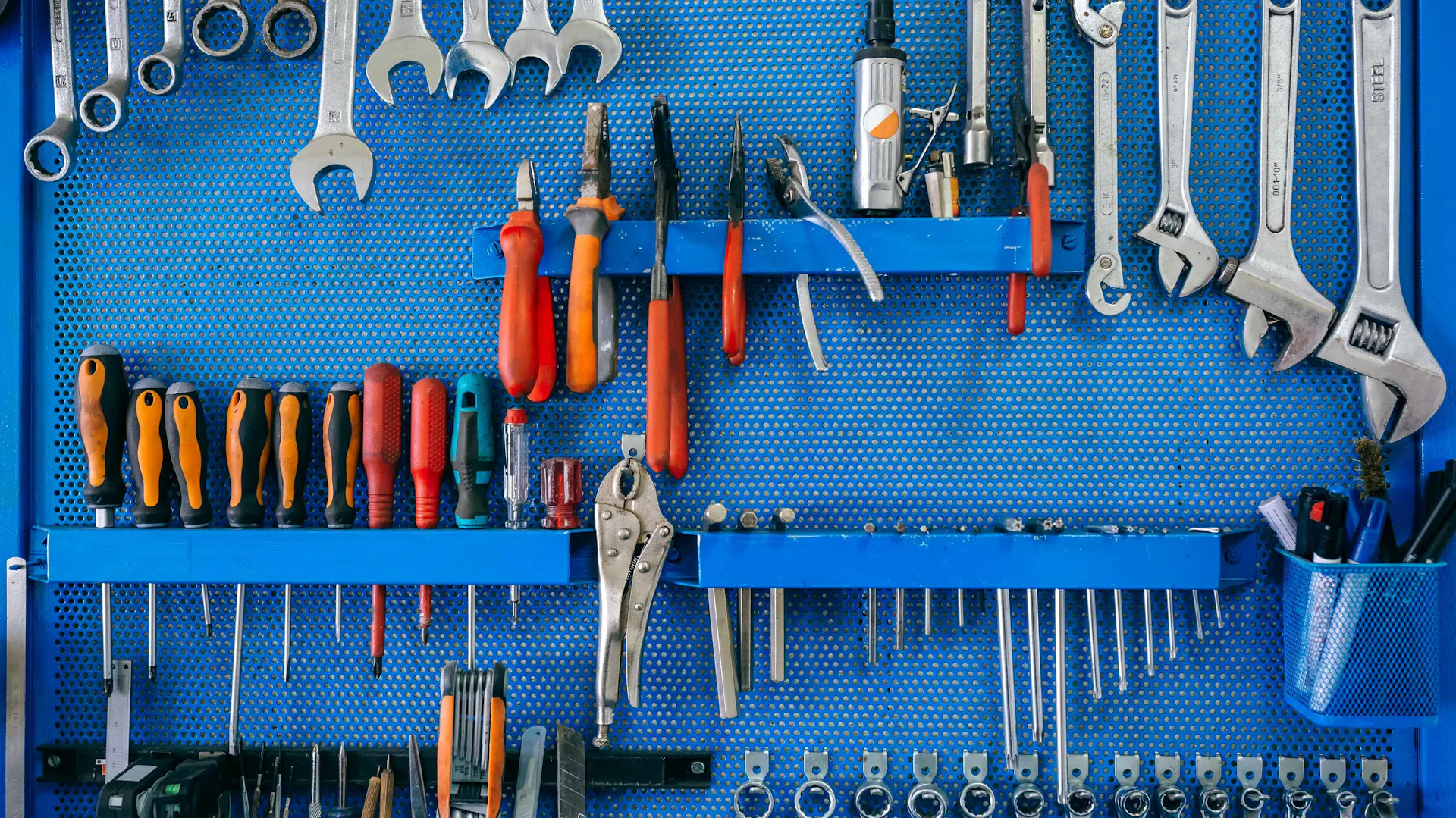 Mur d'outils bleu avec différents tournevis, clés à molette, pinces, etc.
