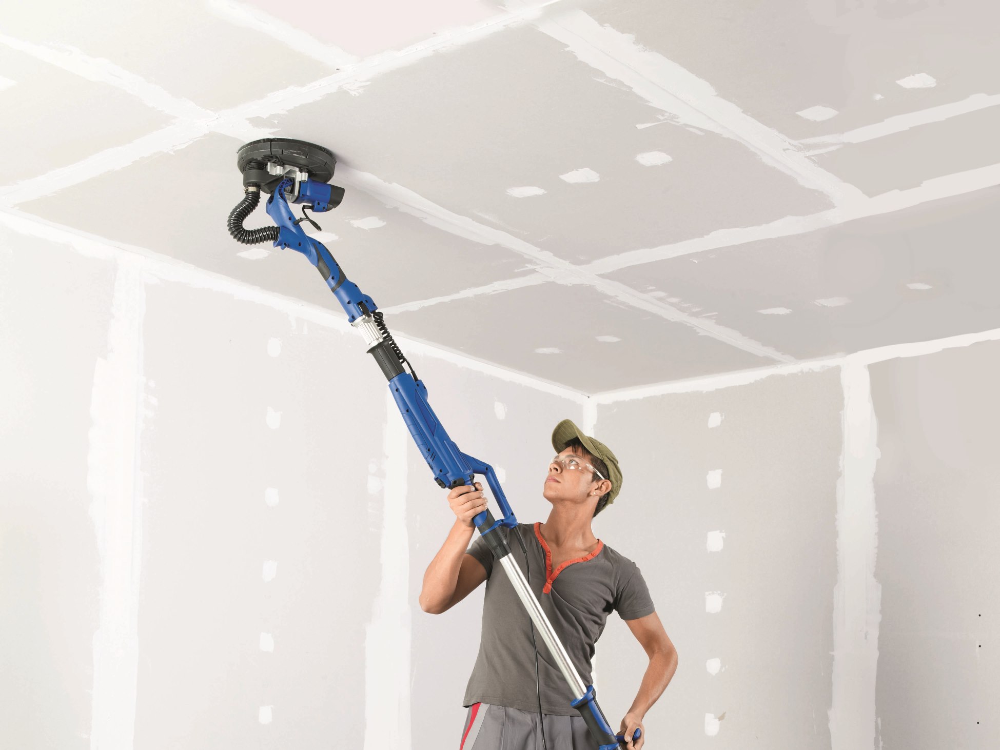 Un appassionato del fai da te tratta il rivestimento del soffitto con la levigatrice per cartongesso