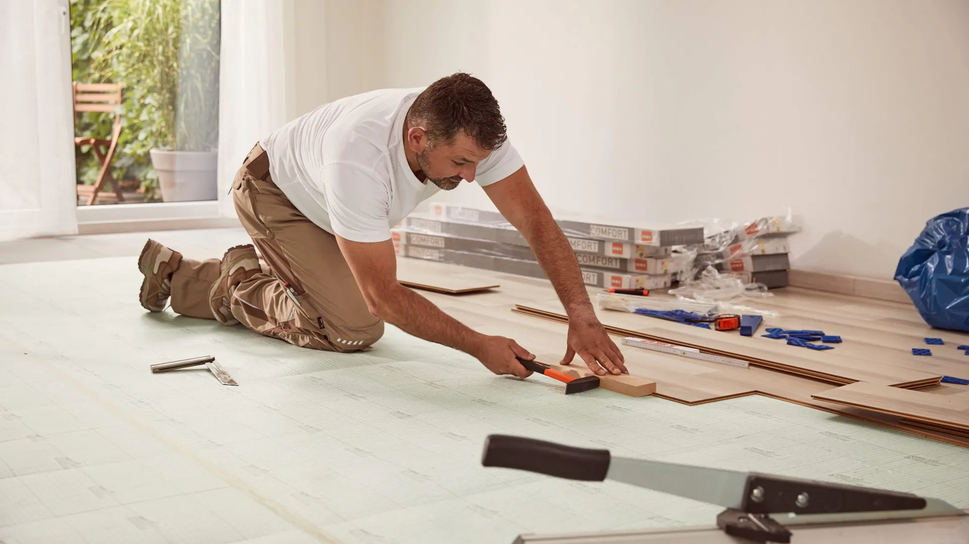 Un bricoleur pose du stratifié avec un marteau et une cale de frappe