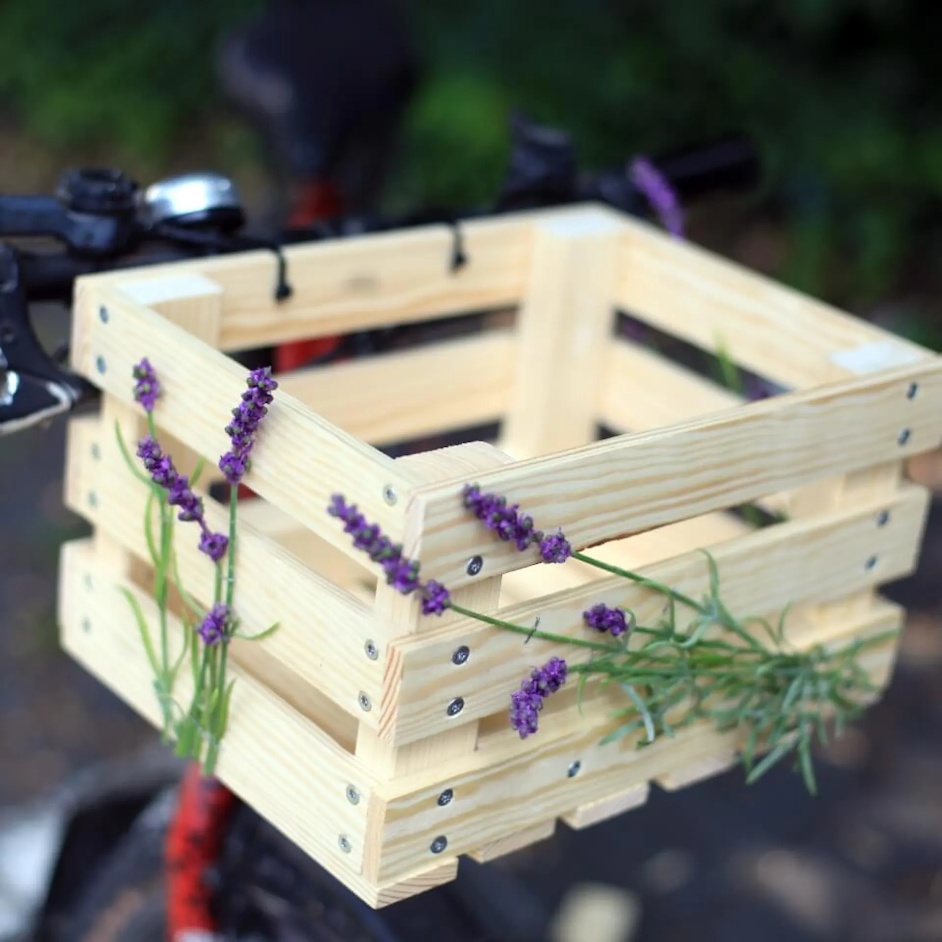 Fahrradkorb, mit Blumen verziert, am Lenker eines Fahrrades befestigt.