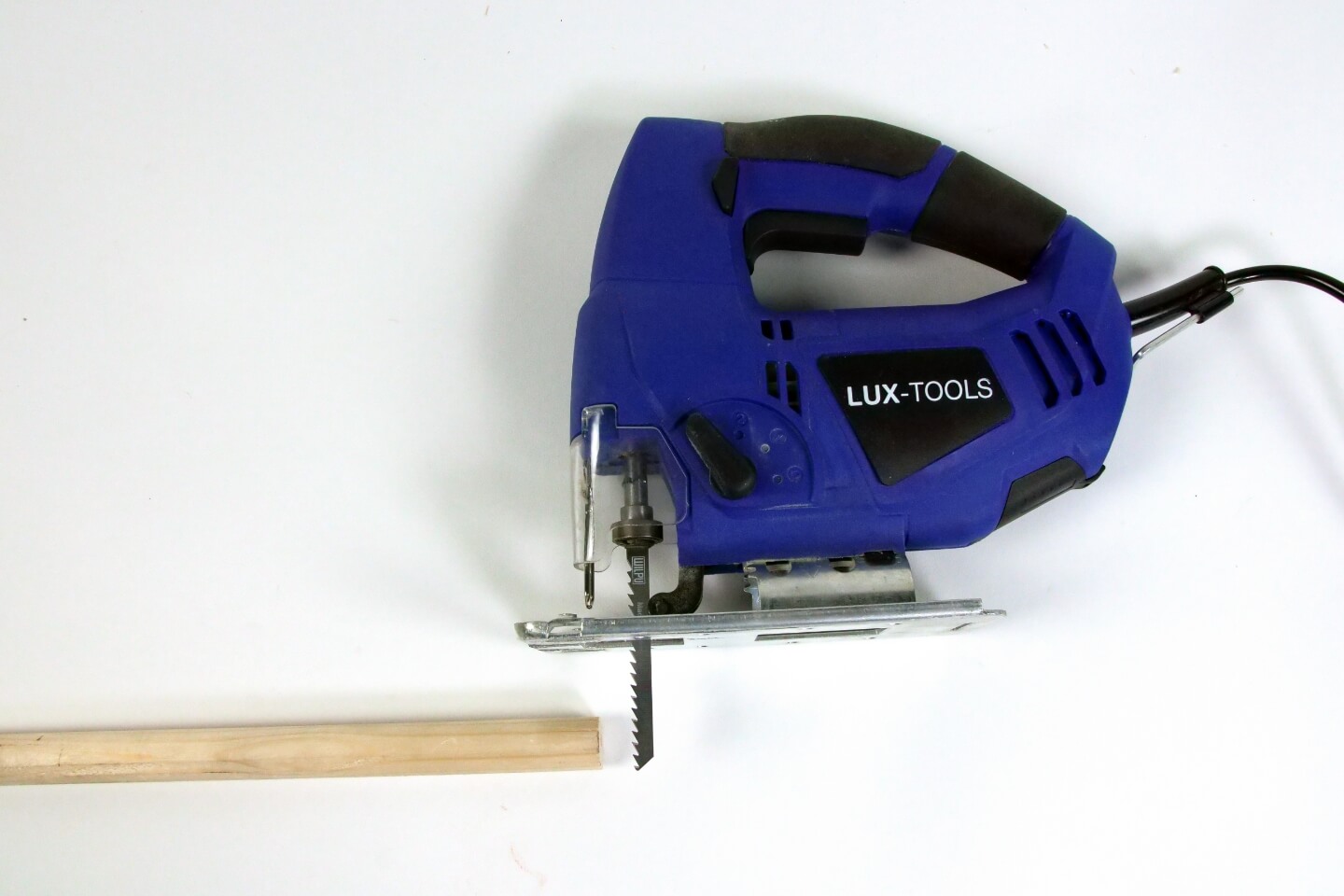 Es ist ein Rundstab aus Holz zu sehen. Daneben liegt eine blaue Stichsäge.
