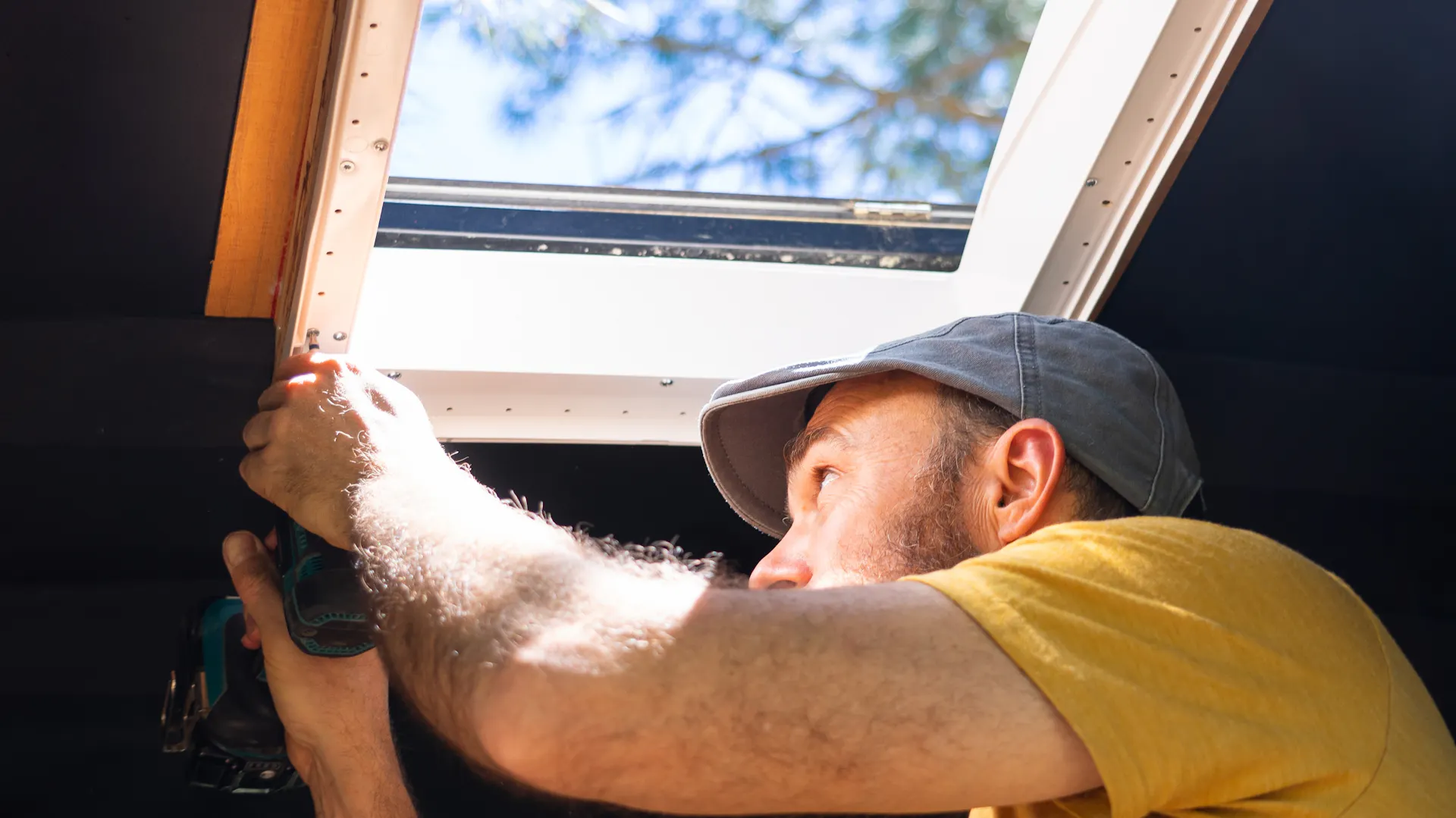 Mann arbeitet von innen am Dachfenster