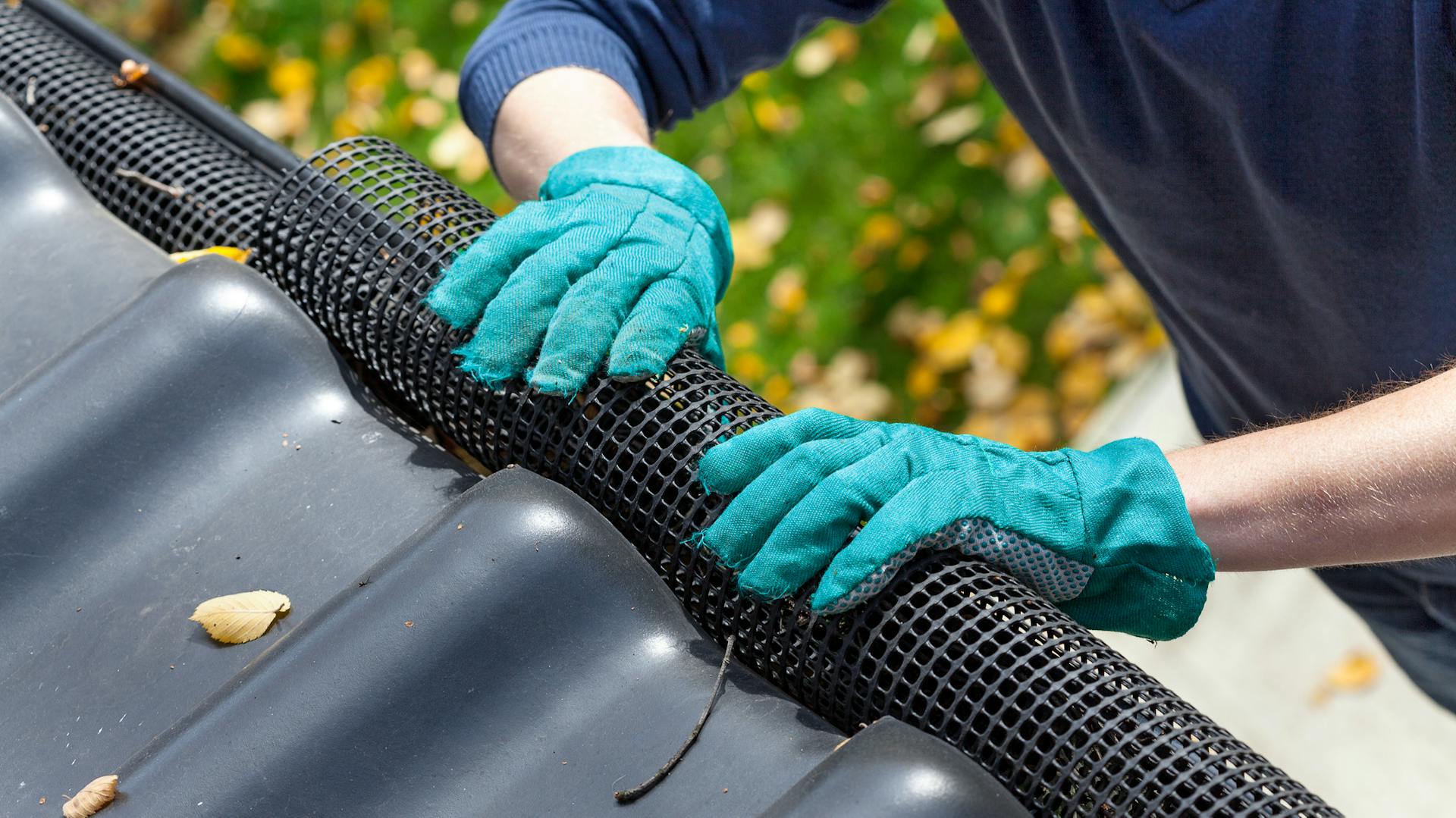 Amante del fai-da-te applica la griglia parafoglie alla grondaia come protezione dalla sporcizia.