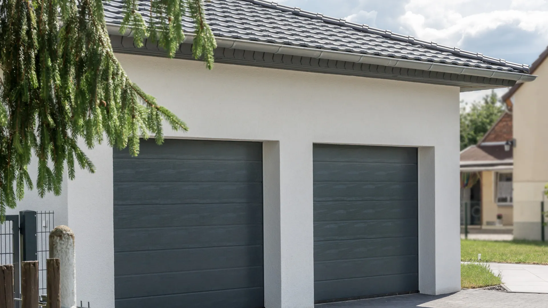 Weiße Doppelgarage mit dunklen Garagentoren.
