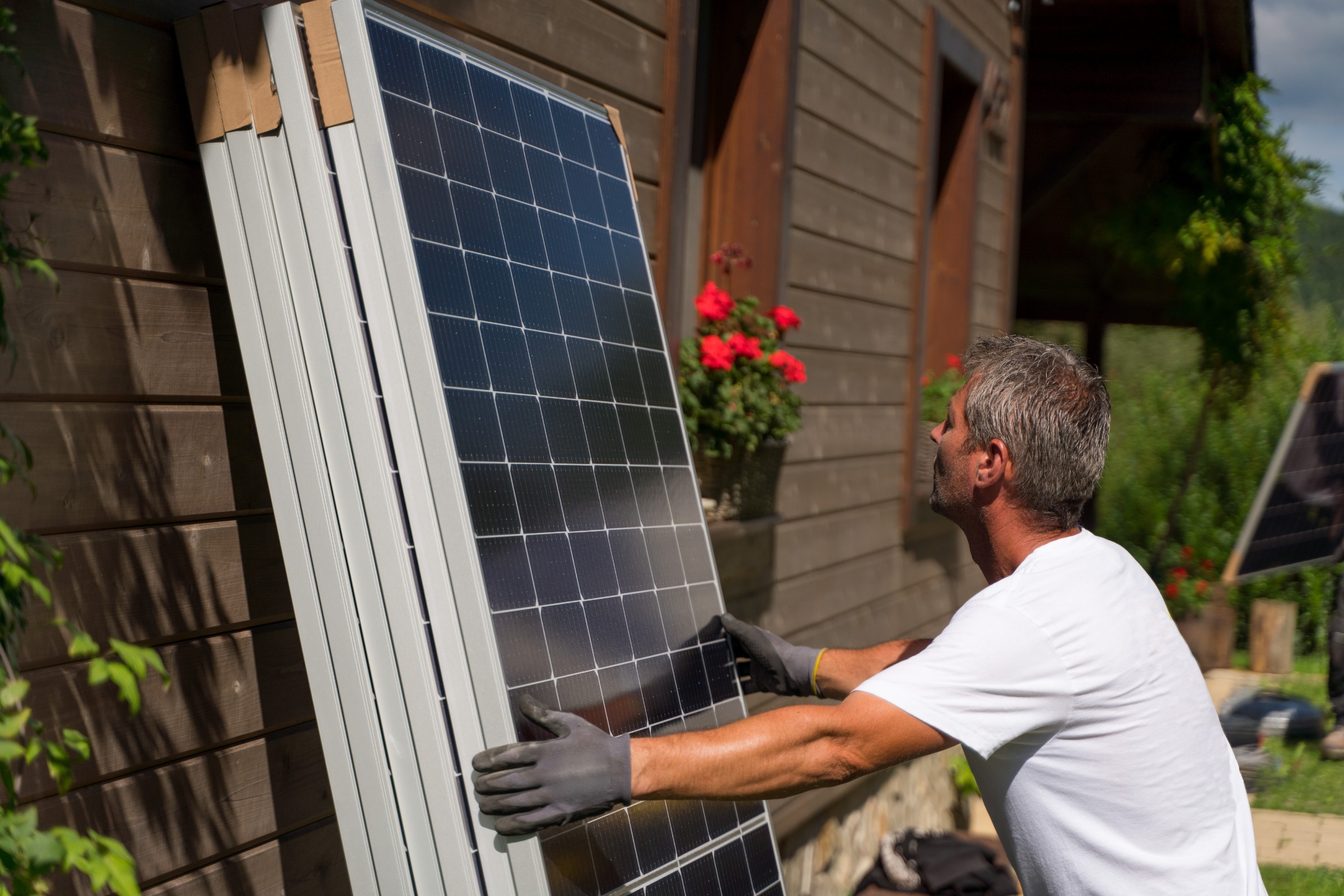 Ein Mann hebt ein Photovoltaik-Panel an