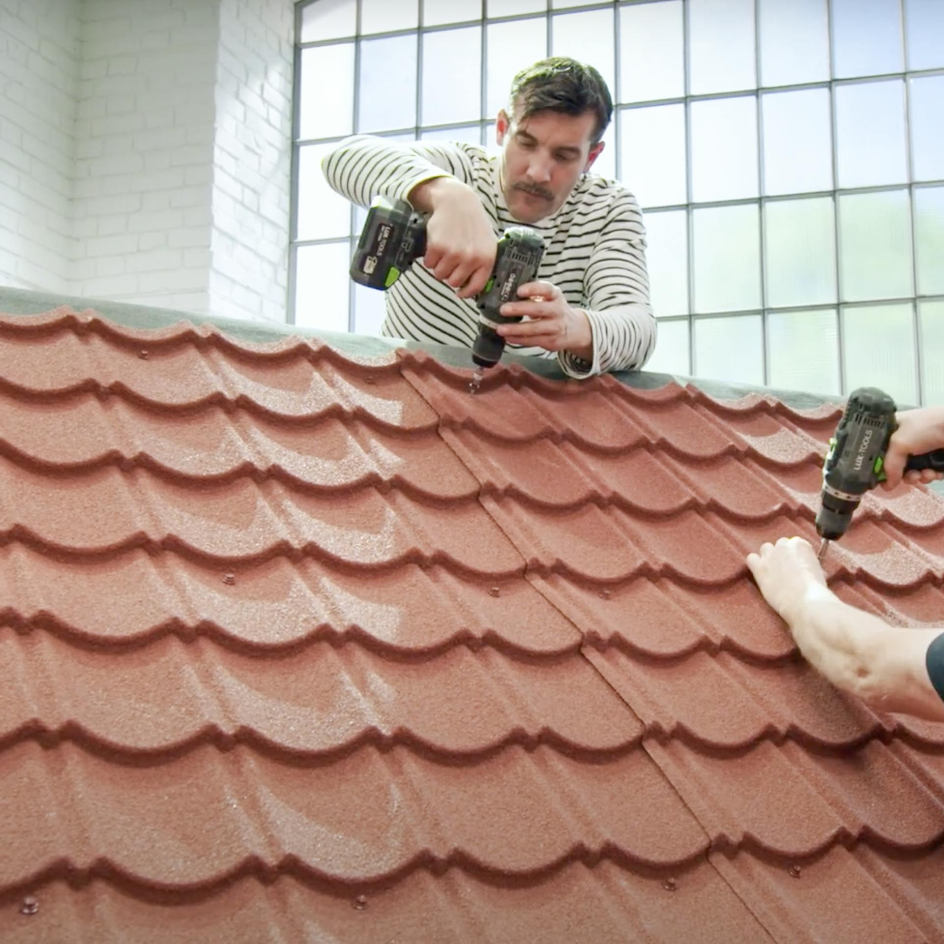 Handwerker verschrauben die Dachbleche auf dem Dach.