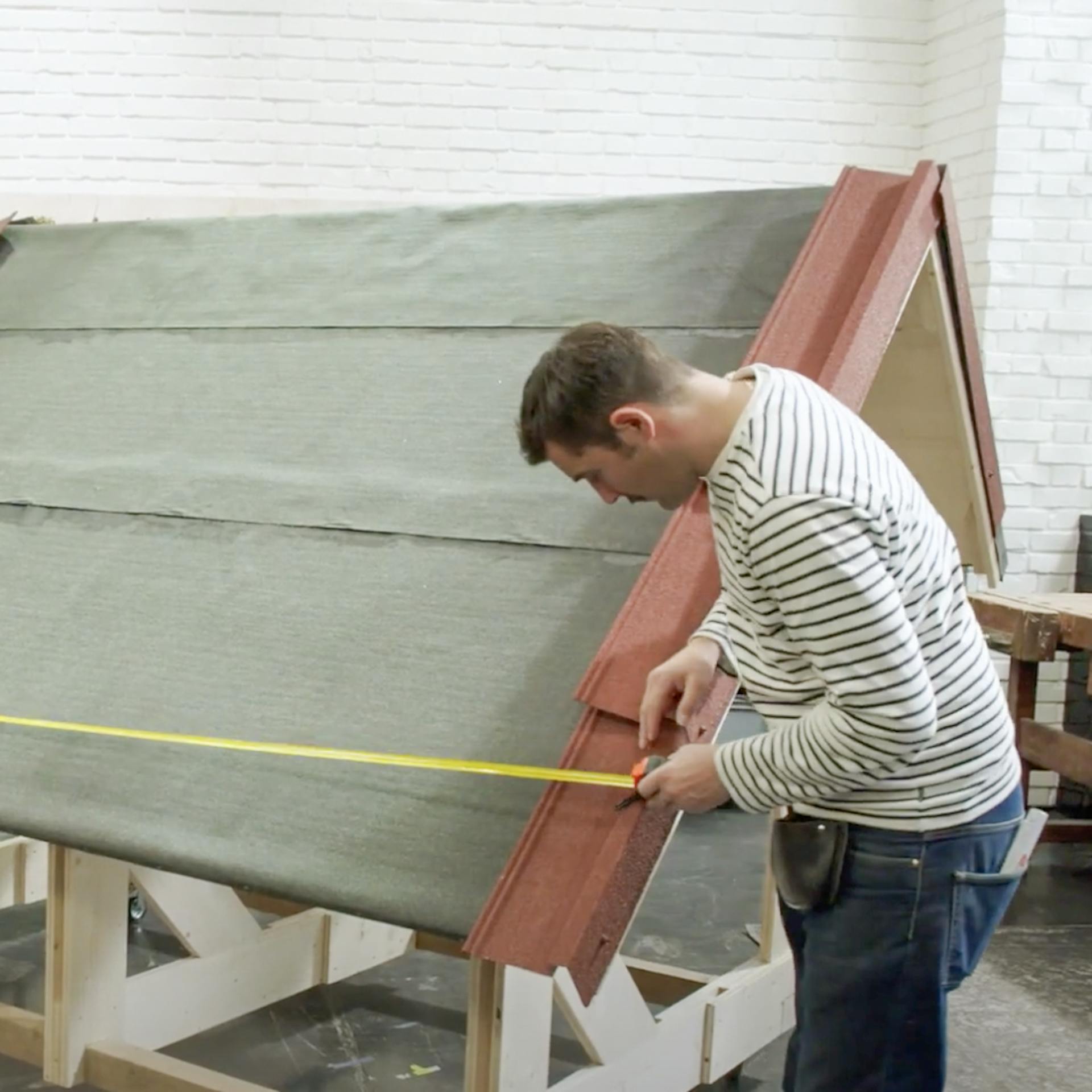 Handwerker hält einen Zollstock an die Seiten des Dachs.