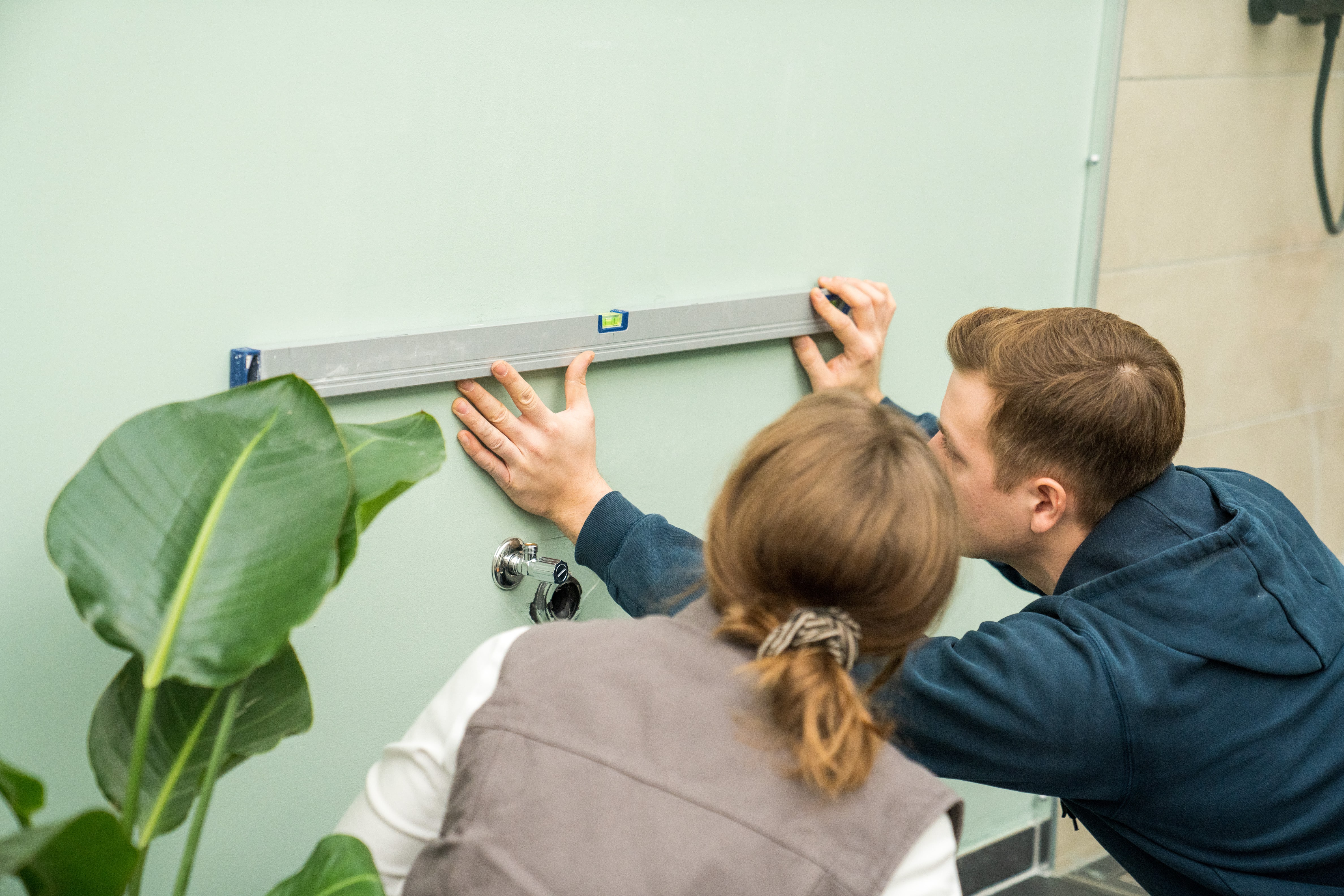 Heimwerker markieren die Abstände für Wandträger eines Aufsatzwaschbeckens.