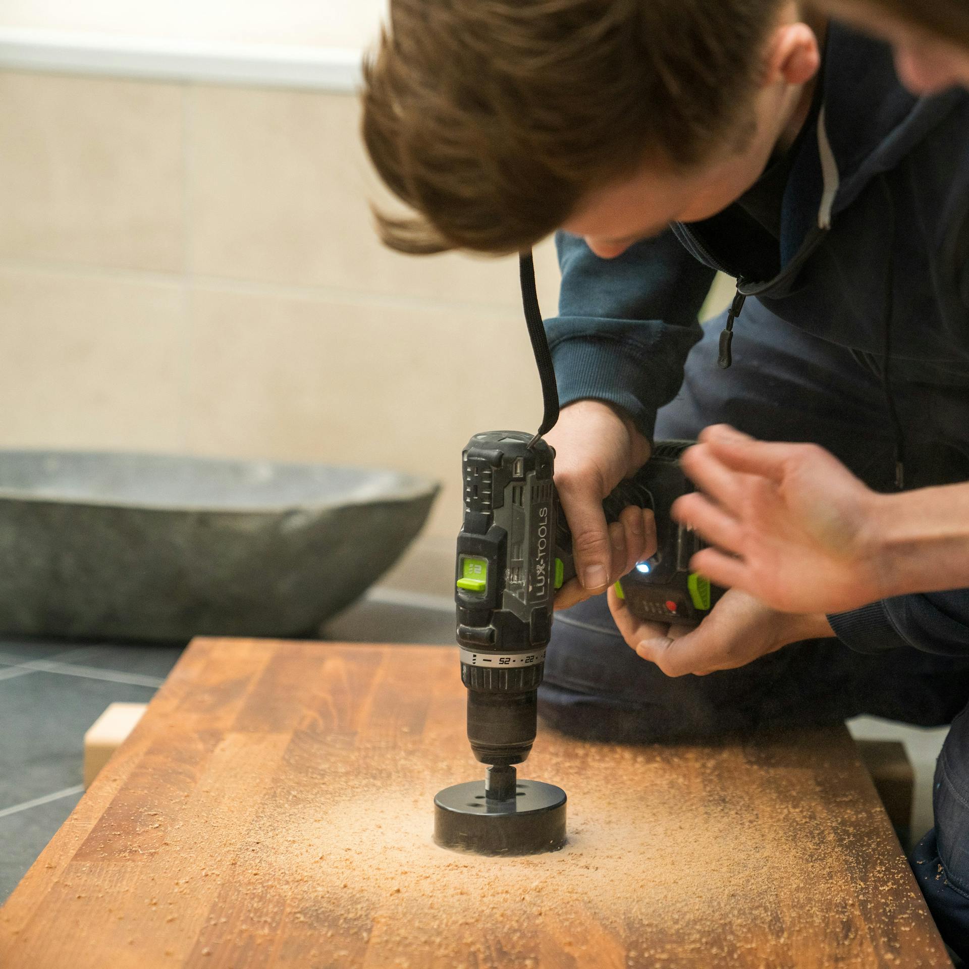 Heimwerker sägen ein Loch für das Abflussrohr in eine Platte.