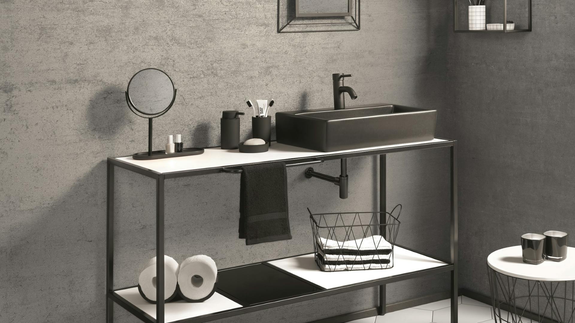 Bad mit Wand in Betonoptik, dunkelgrauen Metallmöbeln und Dekoration sowie wabenförmigen Fliesen