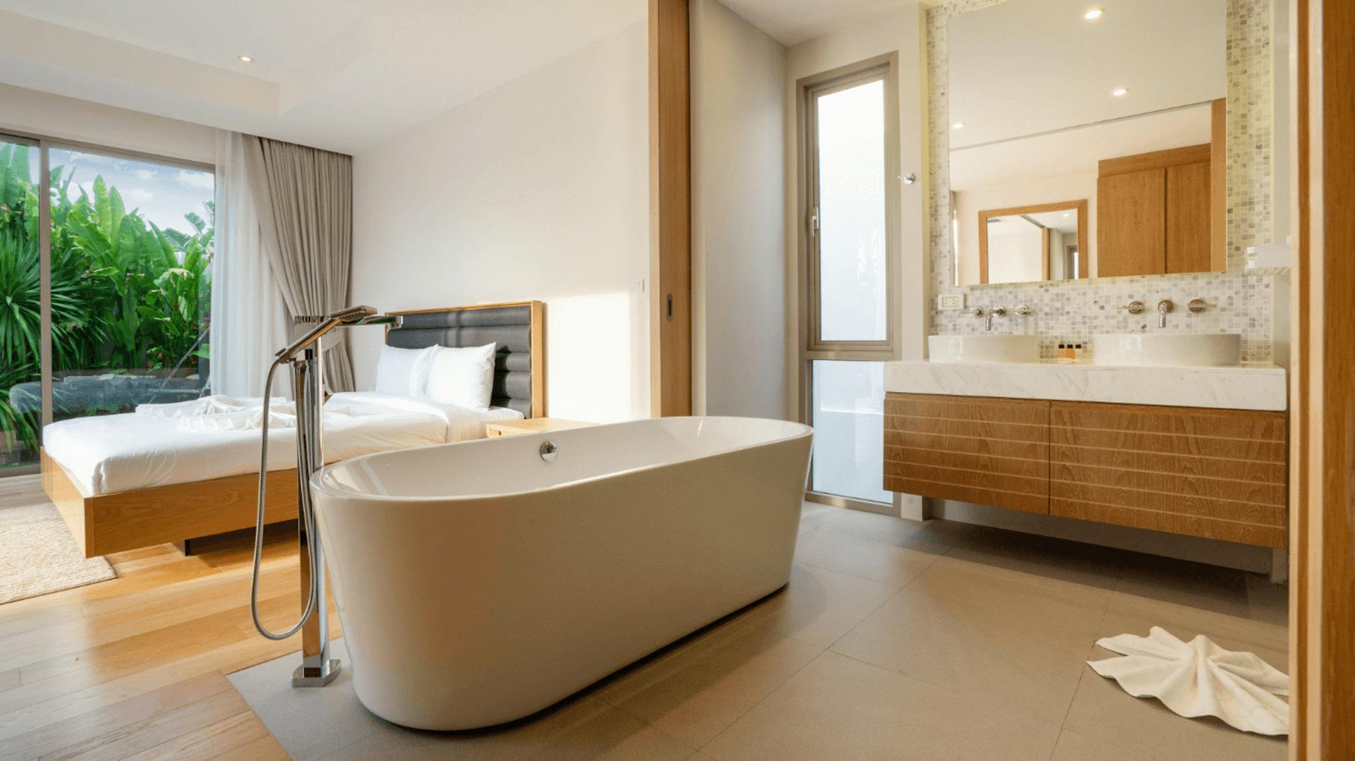 Helles Bad en Suite mit beigefarbener Badewanne und Waschtisch sowie Bett aus Holz.
