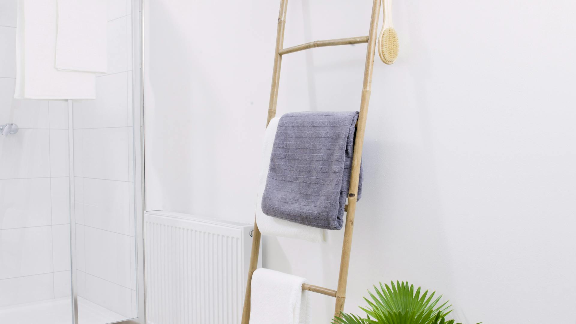 Pflanze und Holzleiter als Handtuchhalter im Bad.