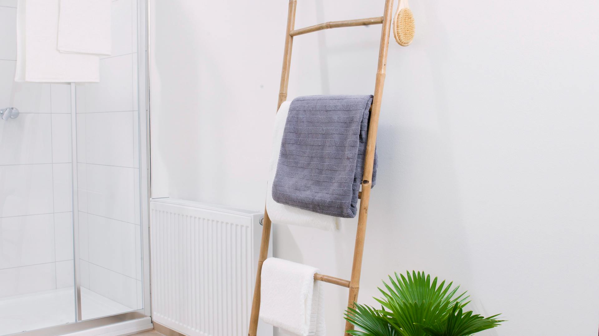 Pflanze und Holzleiter als Handtuchhalter im Bad.