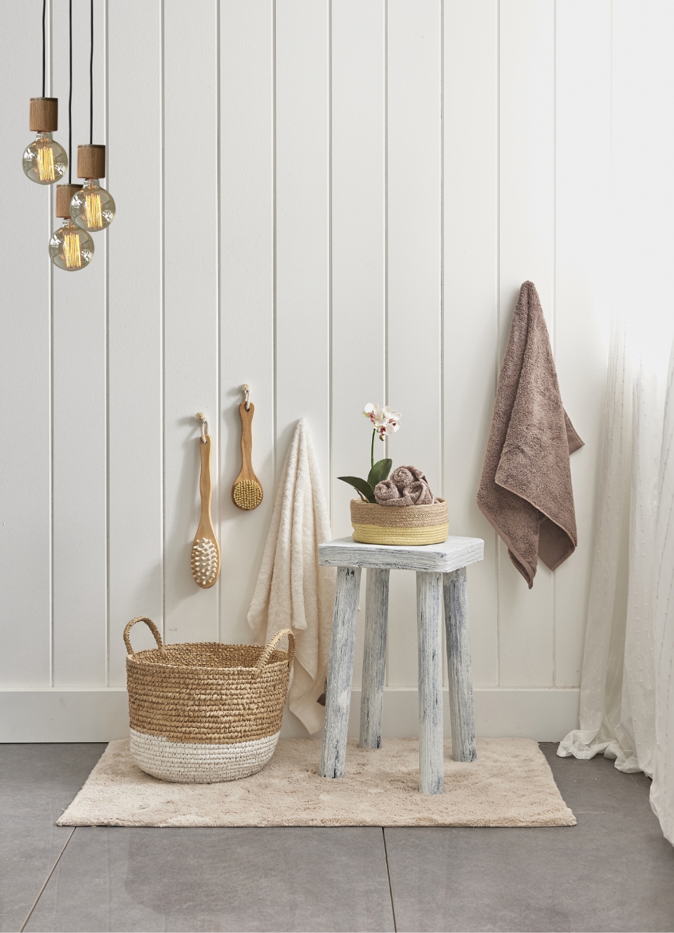 Svetlomodrý stolček, vedľa neho prútený košík pred bielou obloženou stenou.