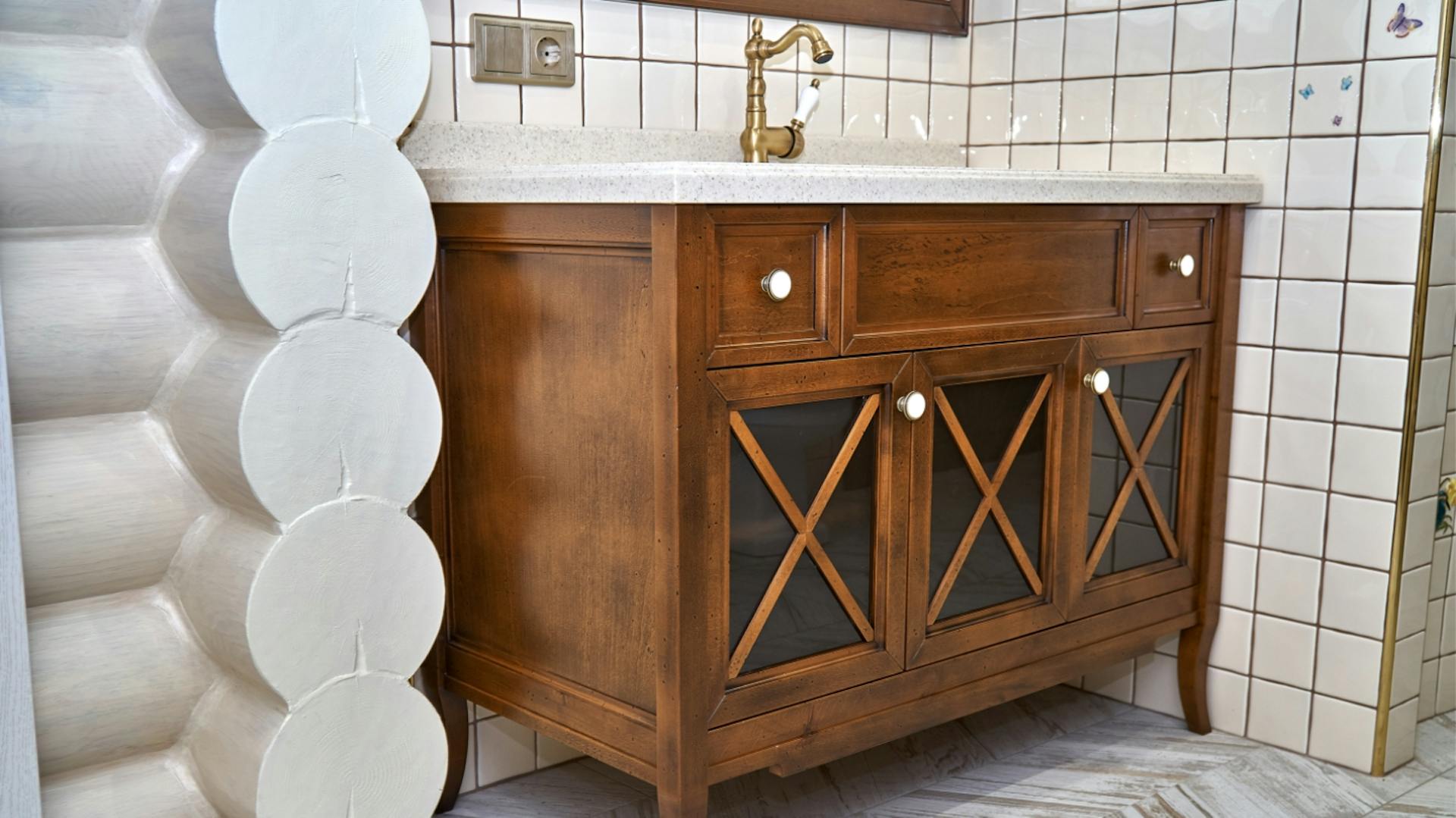 Waschtisch aus Holz im Landhausstil mit weißem Waschbecken und goldenem Wasserhahn.