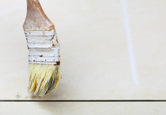 Un pennello con smalto su delle piastrelle.