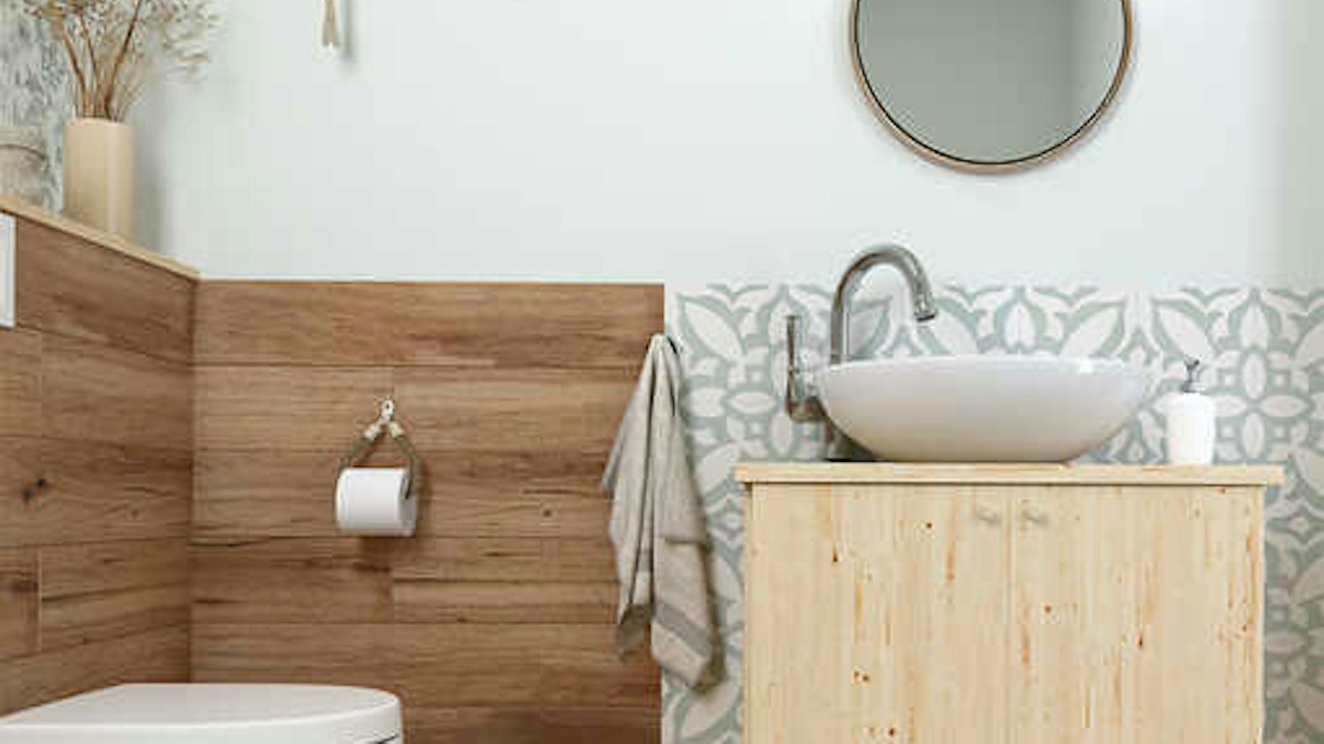 Ein Badezimmer mit einer Wandverkleidung aus Holz und hellen Holzmöbeln.