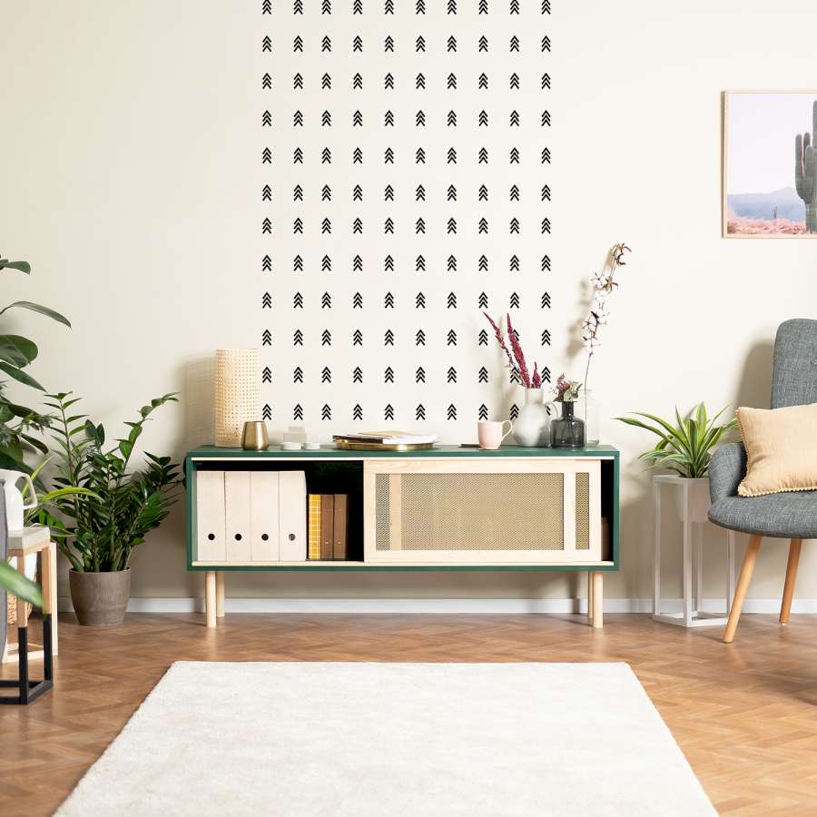 Tape Art an einer Wand hinter einem niedrigen, grünen Regal