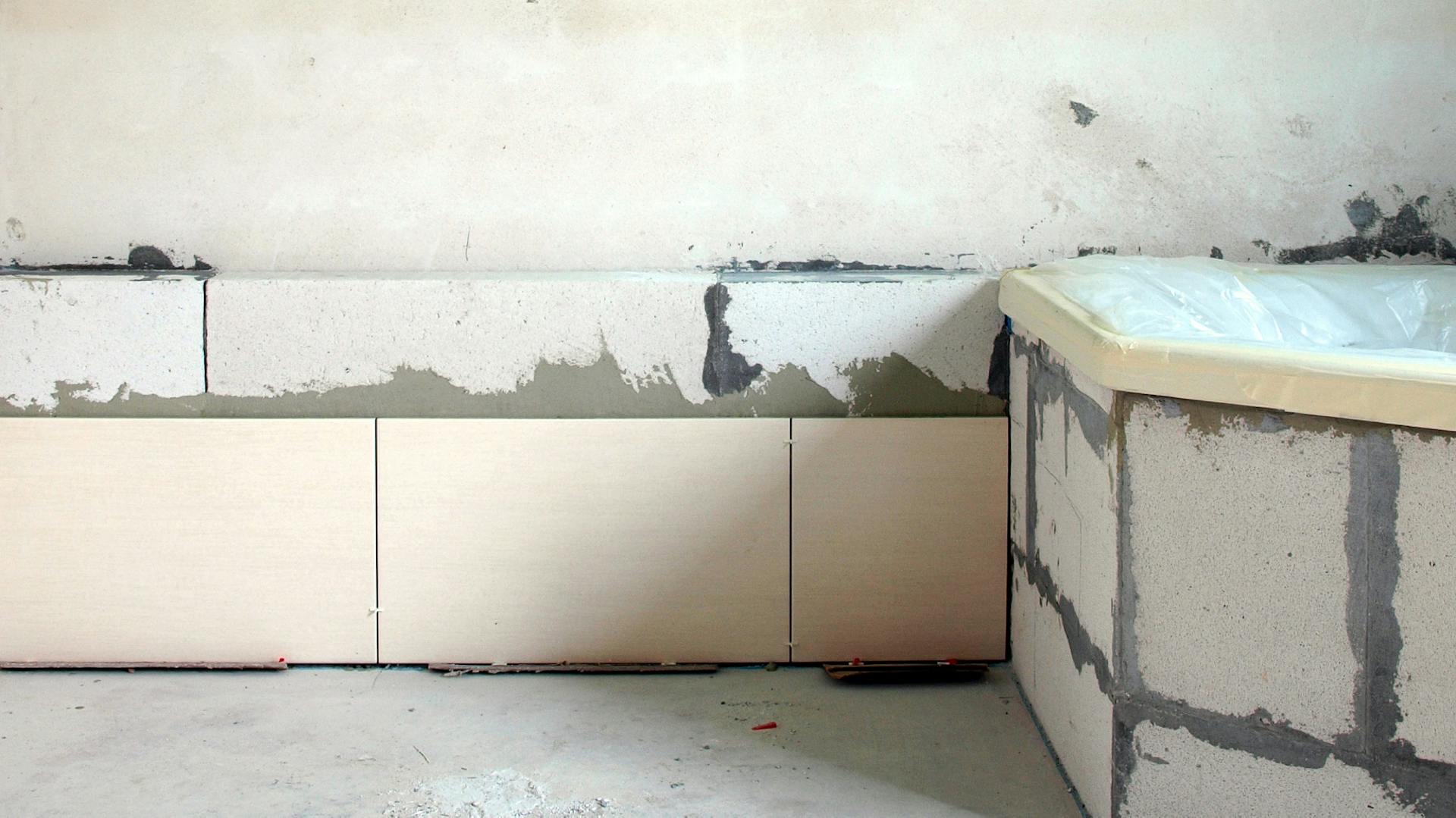 Rohbau eines Badezimmers mit Badewanne, in dem Bauplatten verlegt werden.