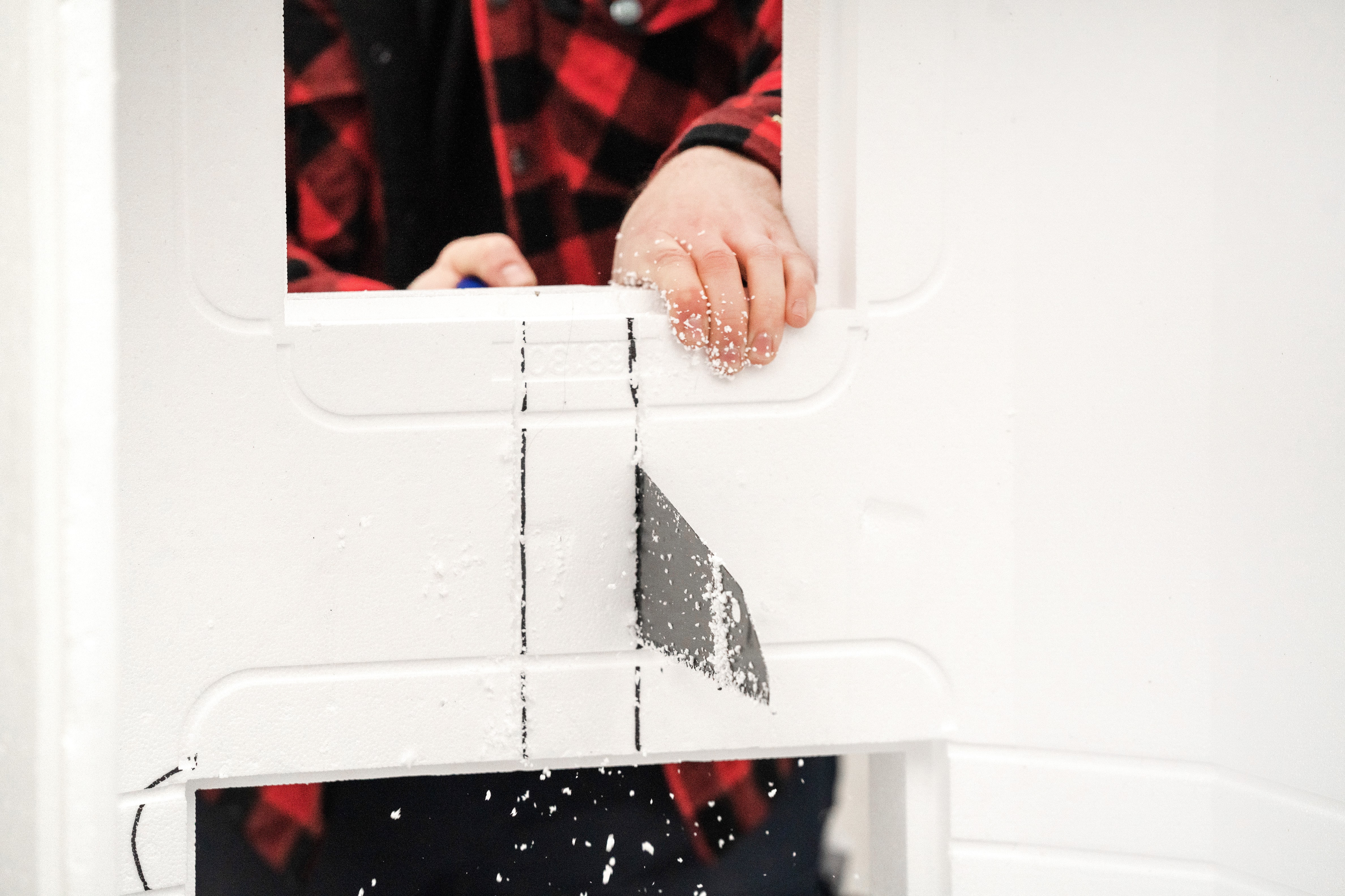 Jemand schneidet markierte Stellen mit einem Fuchsschwanz aus einem Wannenträger heraus.