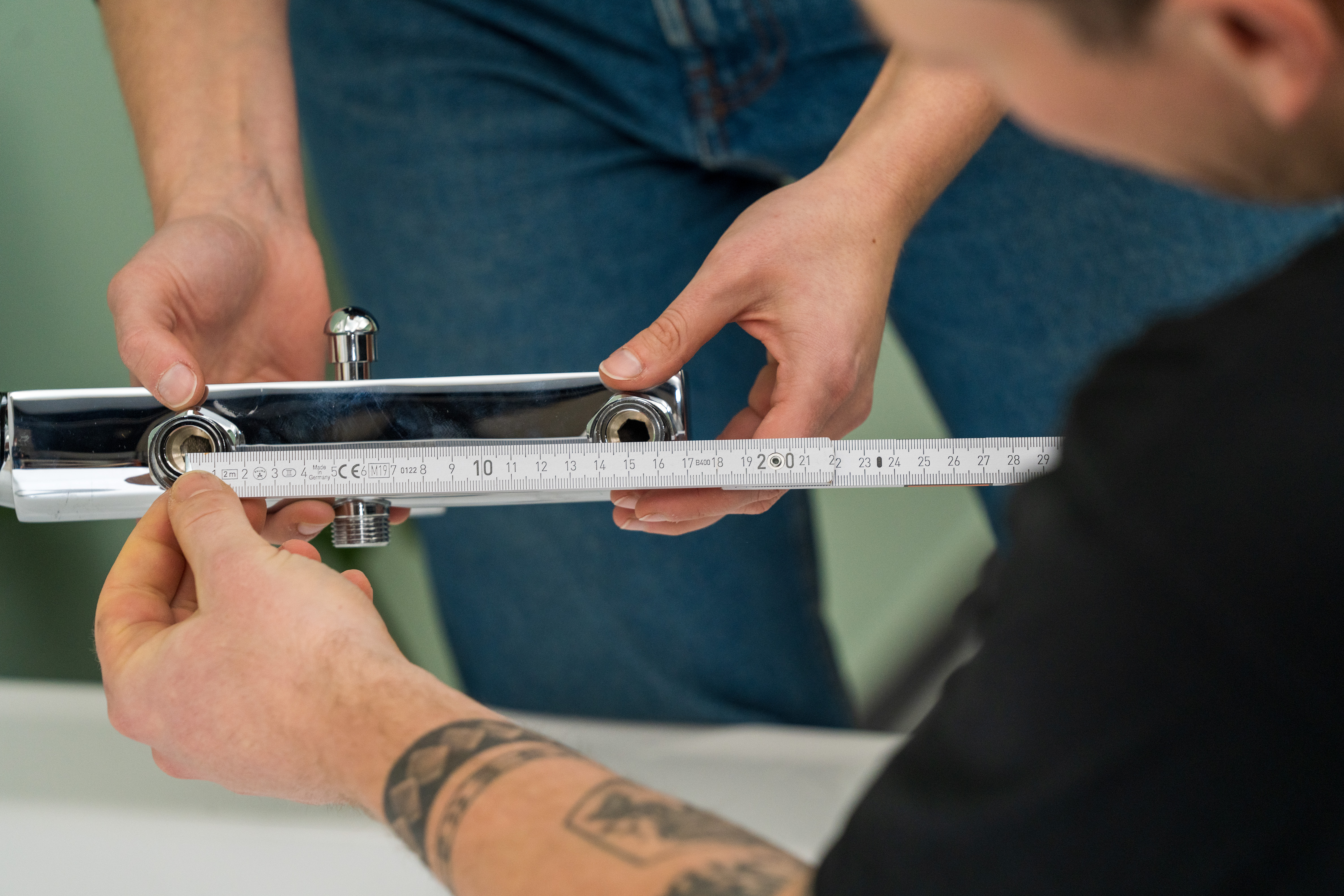 Dvaja pracovníci merajú vzdialenosť medzi prípojkami na batériu skladacím metrom