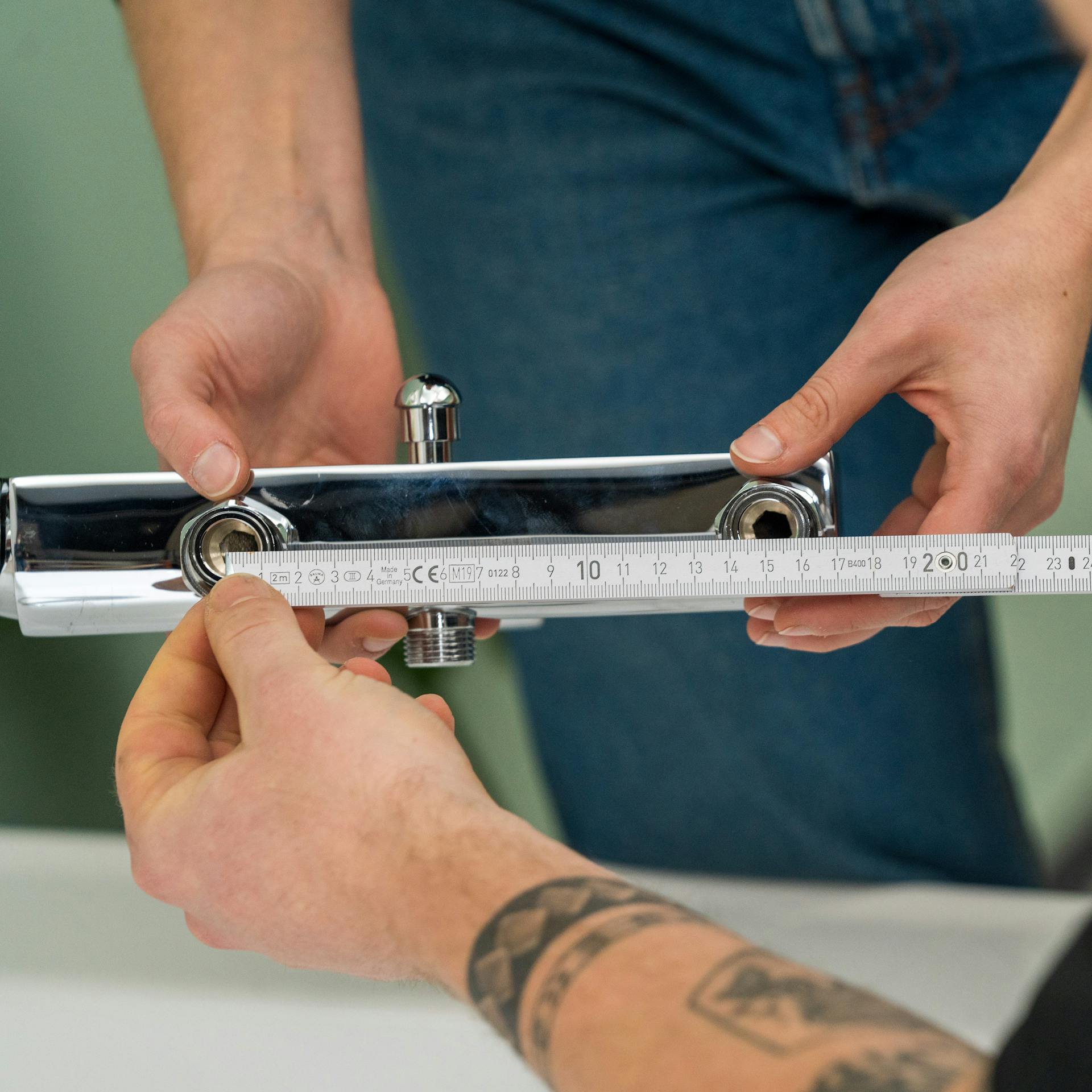 Zwei Handwerker messen den Abstand der Armaturanschlüsse mit einem Zollstock