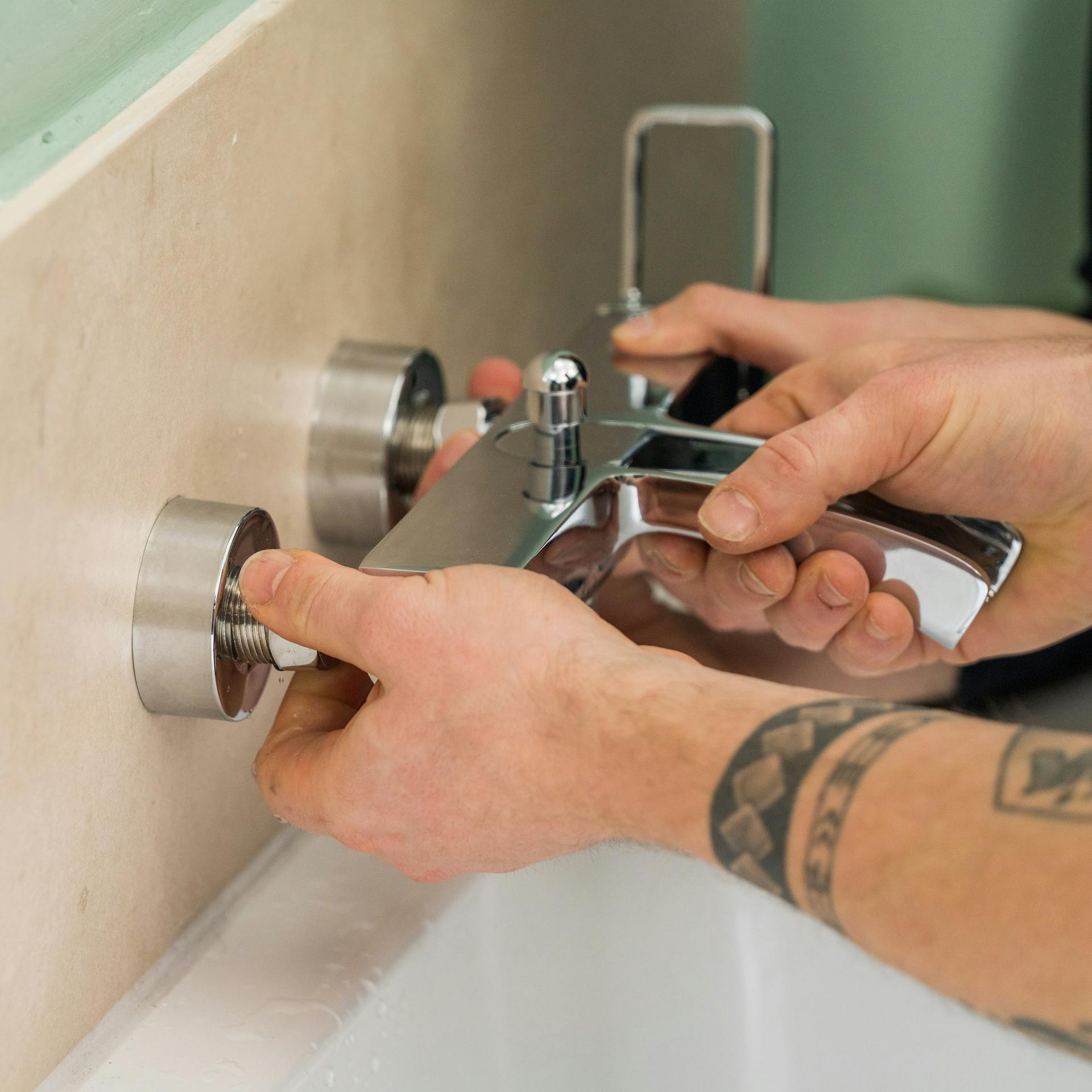 Handwerker bringt die neue Armatur an.