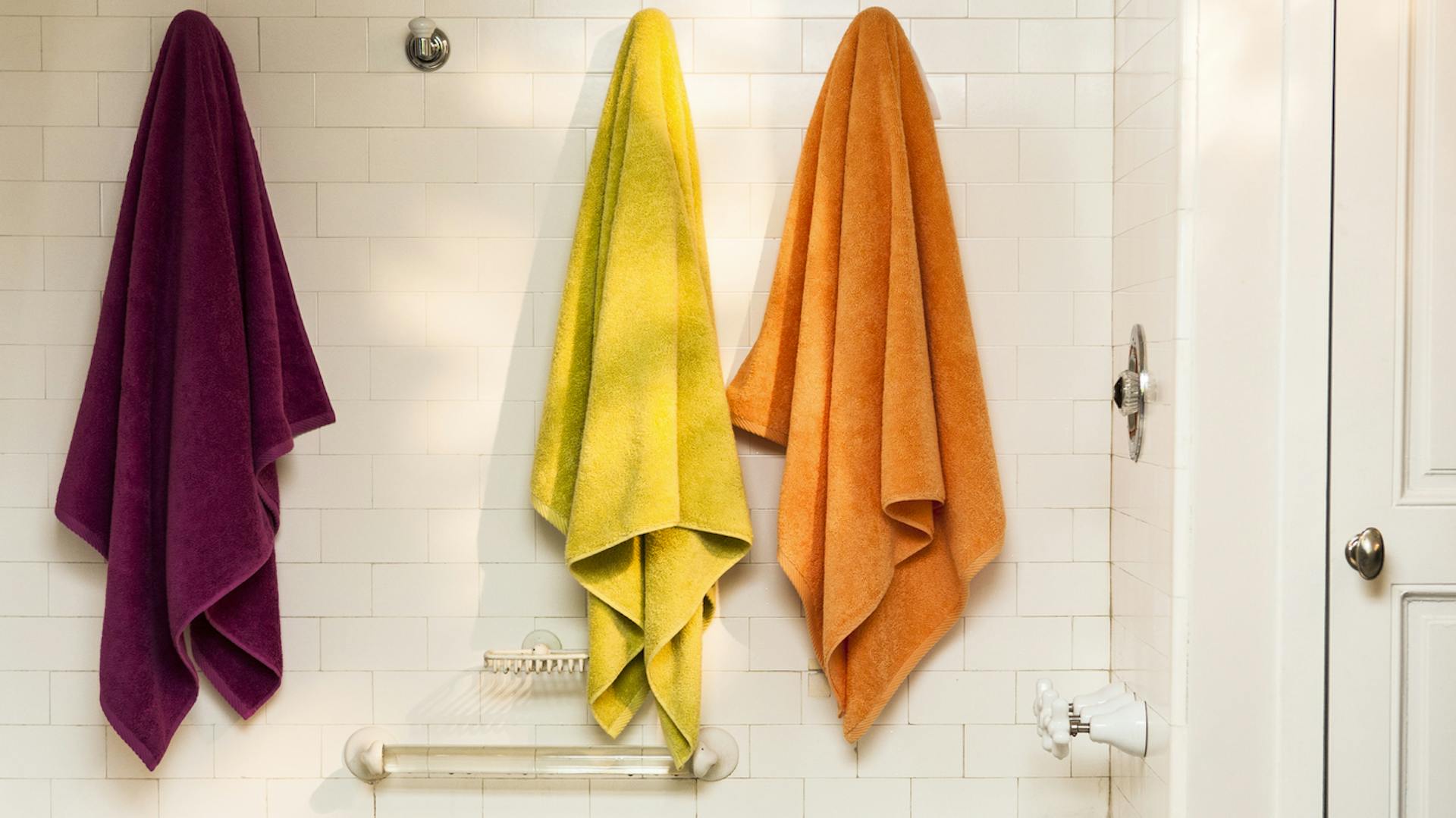 Bunte Handtücher hängen an der Wand im Badezimmer.