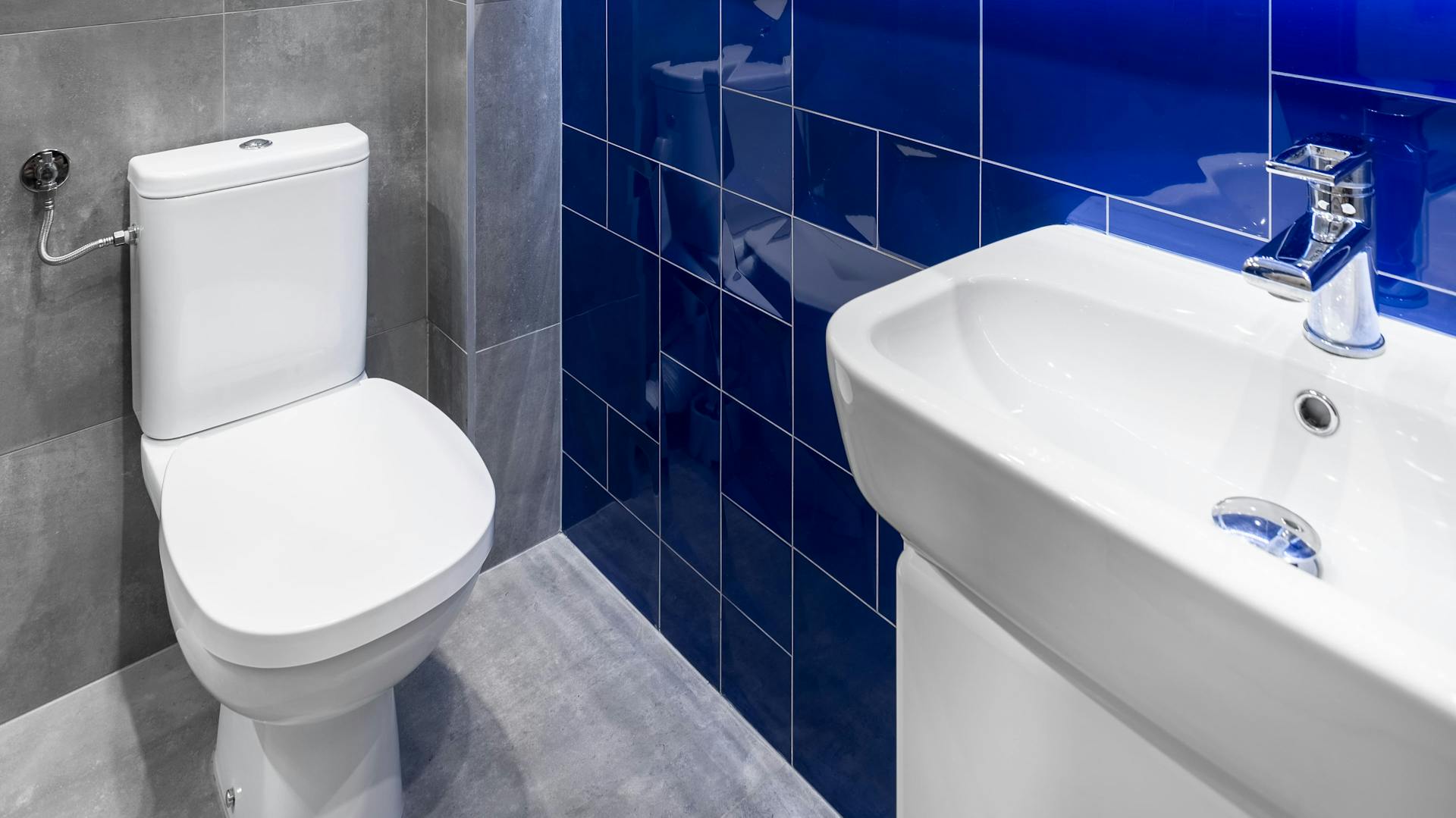 Badezimmer mit grauen und blauen Fliesen.