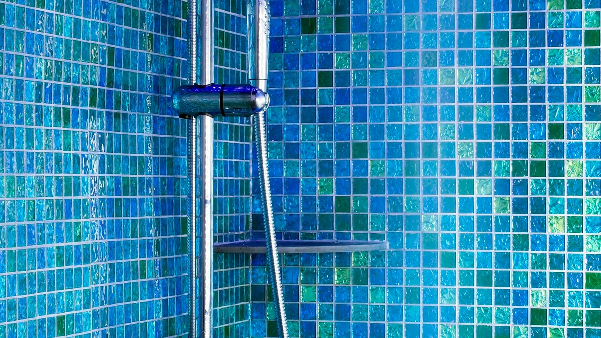 Eine blaue Duschkabine mit Mosaikfliesen.
