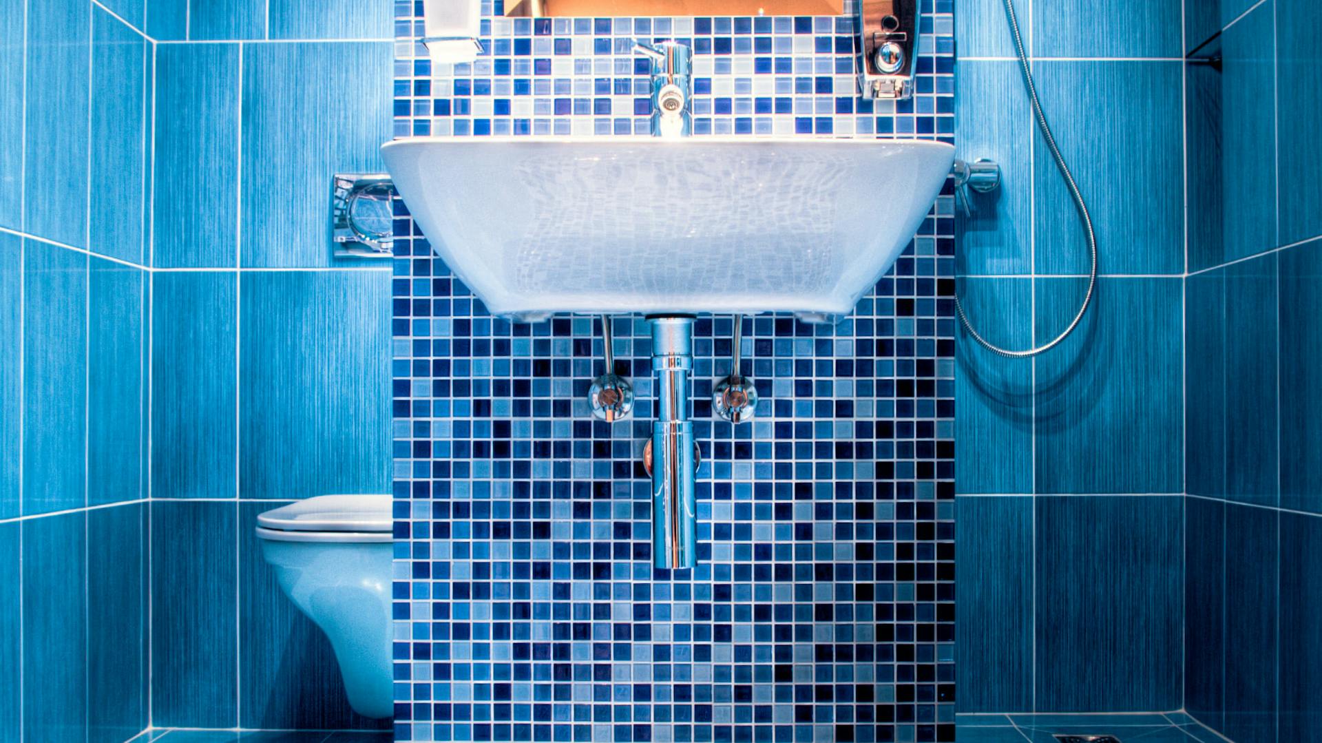 Ein blaues Badezimmer mit Mosaikfliesen.