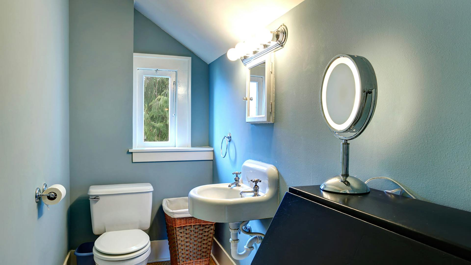 Ein Bad mit blauen Wänden und einer weißen Keramikausstattung.