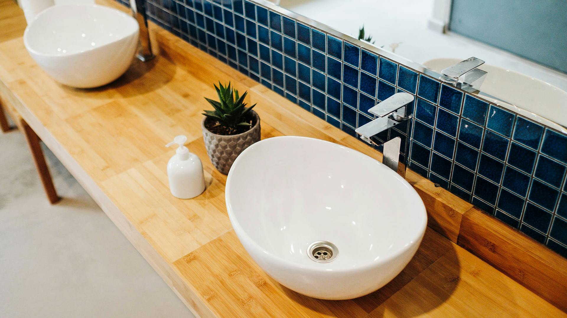 Ein weißes Waschbecken vor blauen Fliesen.