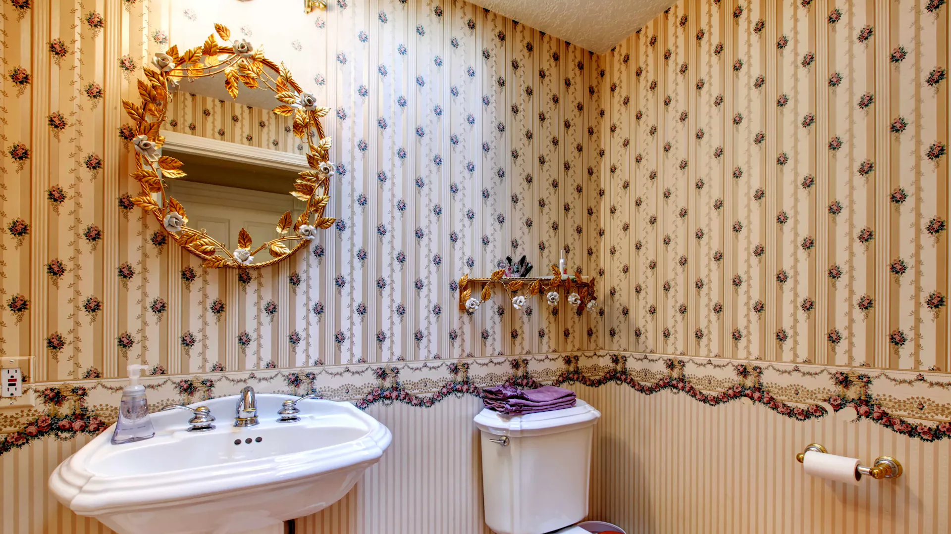 Badezimmer mit goldenem Spiegel.