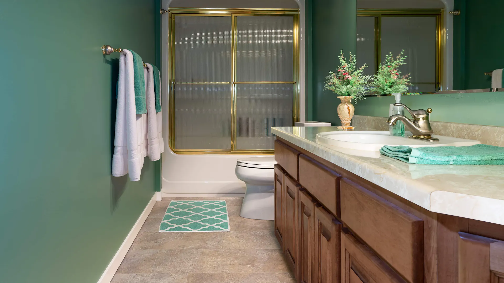 Badezimmer mit braunem Waschtisch und goldenen Armaturen.