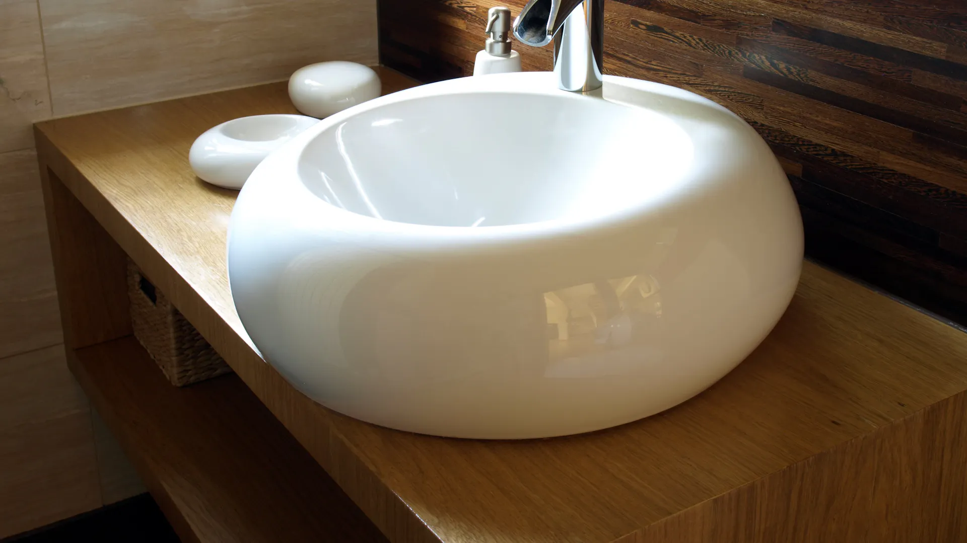 Ein weißes Waschbecken auf einem braunen Waschtisch.