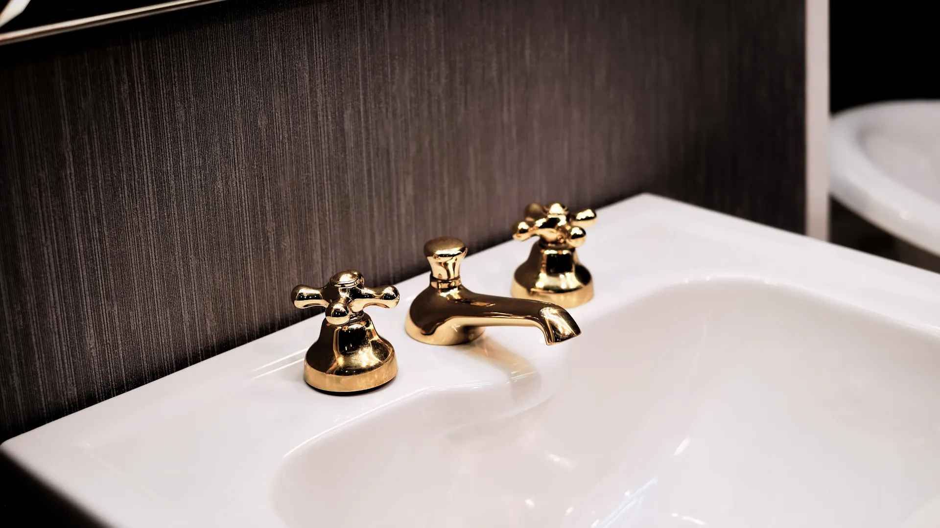 Waschbecken mit goldenem Wasserhahn.