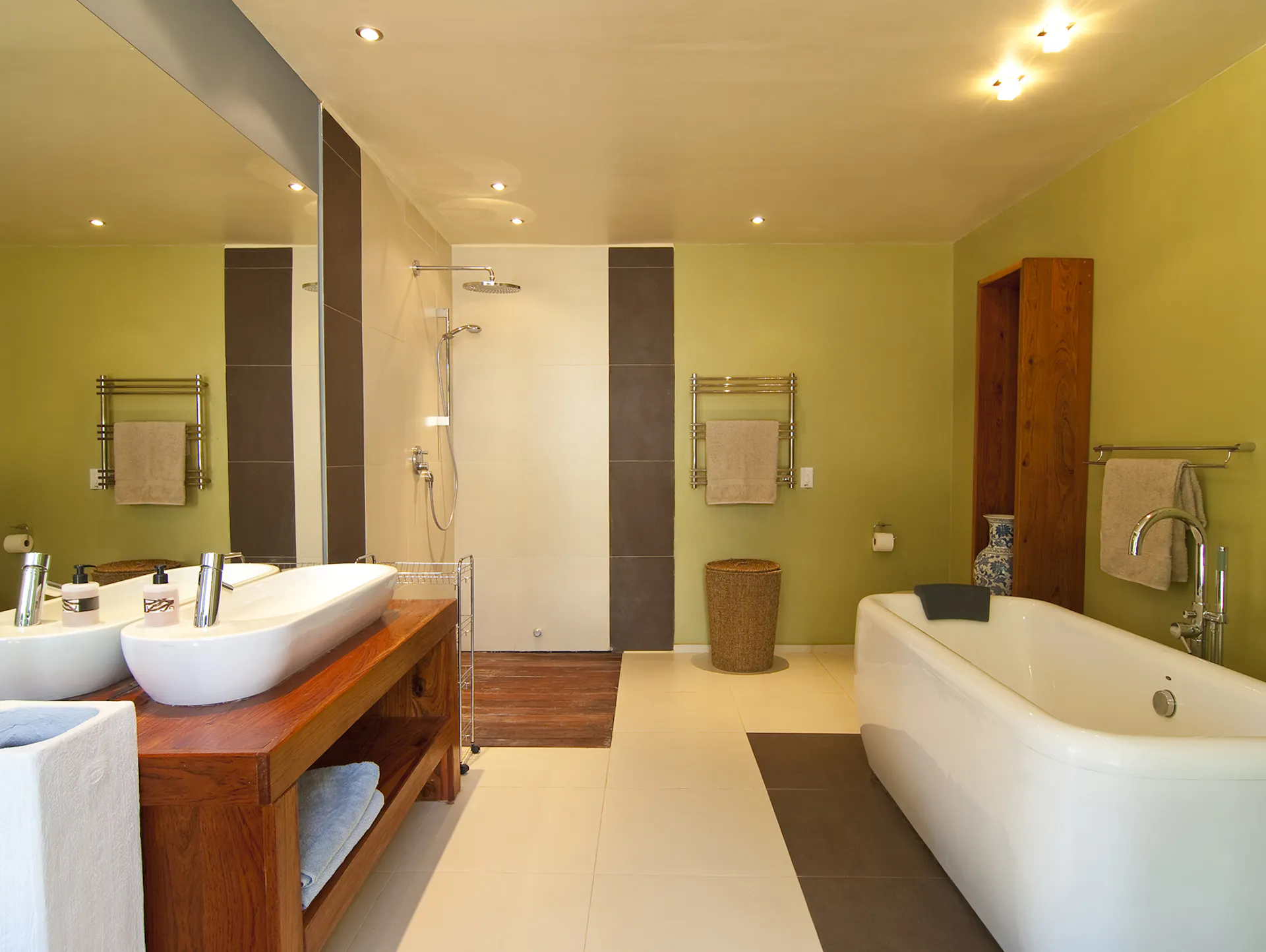 Badezimmer mit Möbeln aus Holz, grünen Wänden und weißen Fliesen