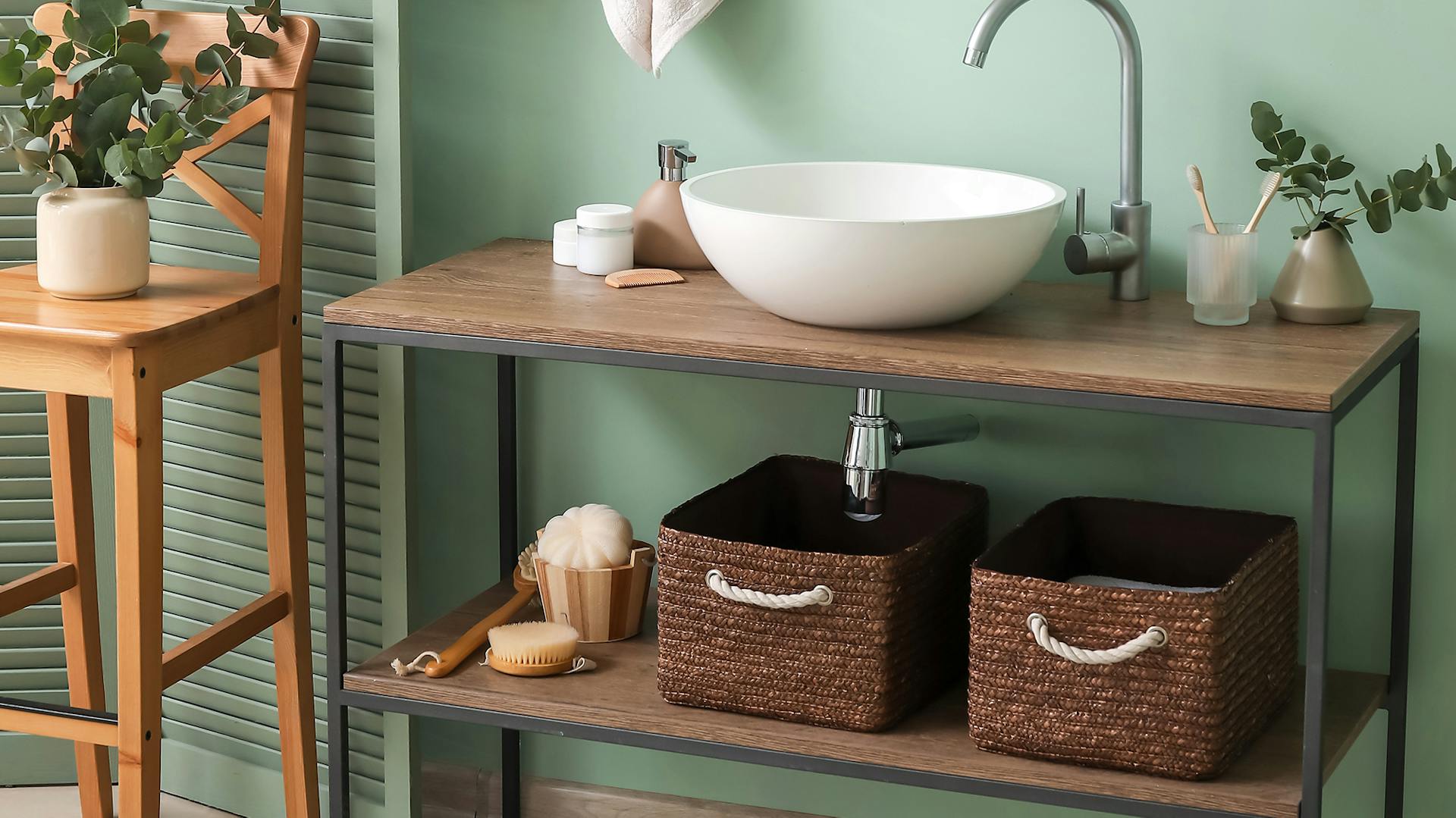 Parete color menta, davanti c’è un mobile lavabo con lavabo bianco. Sopra è posizionato uno specchio esagonale.