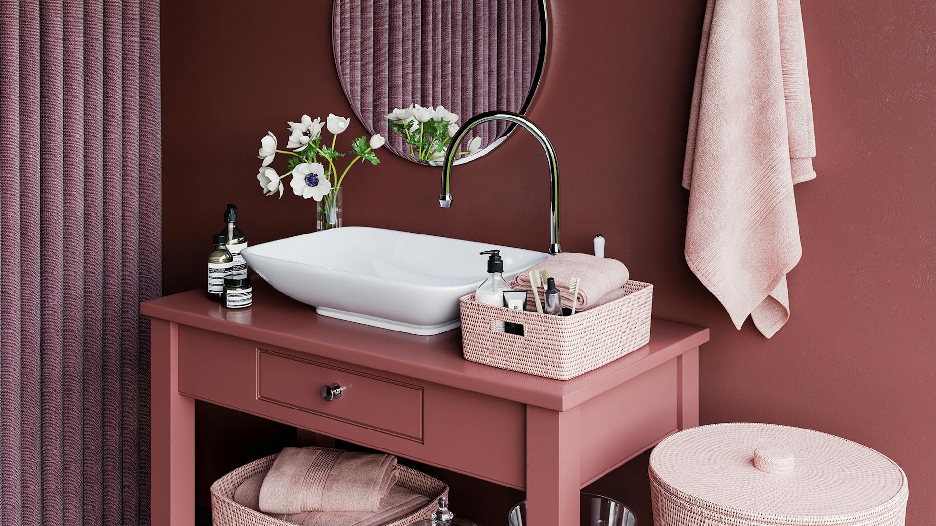 Bagno color rosa antico con mobile lavabo, lavabo bianco e accessori rosa chiaro.
