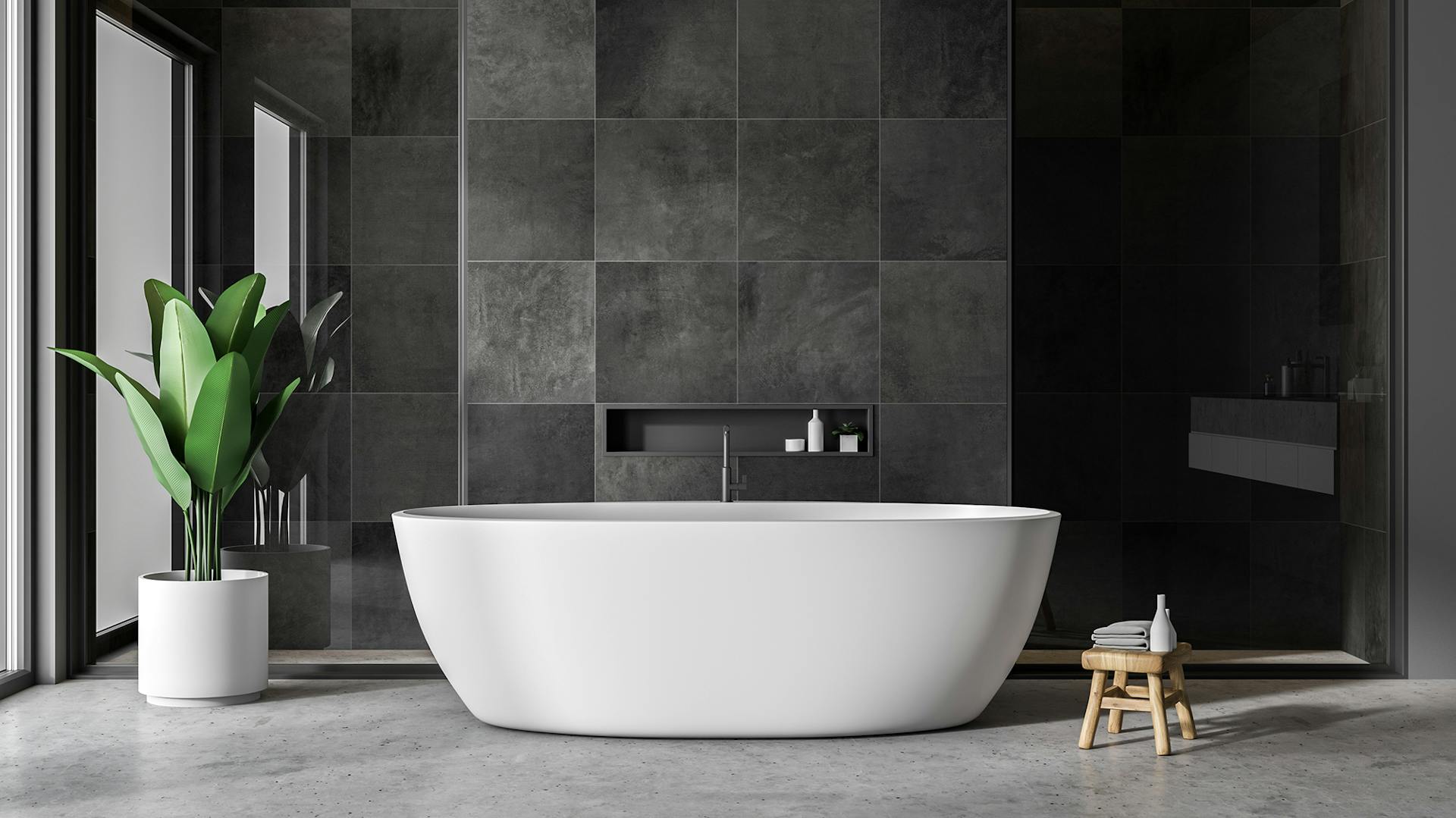 Parete con piastrelle nere, vasca da bagno bianca davanti, pianta verde in vaso bianco all'esterno a sinistra.