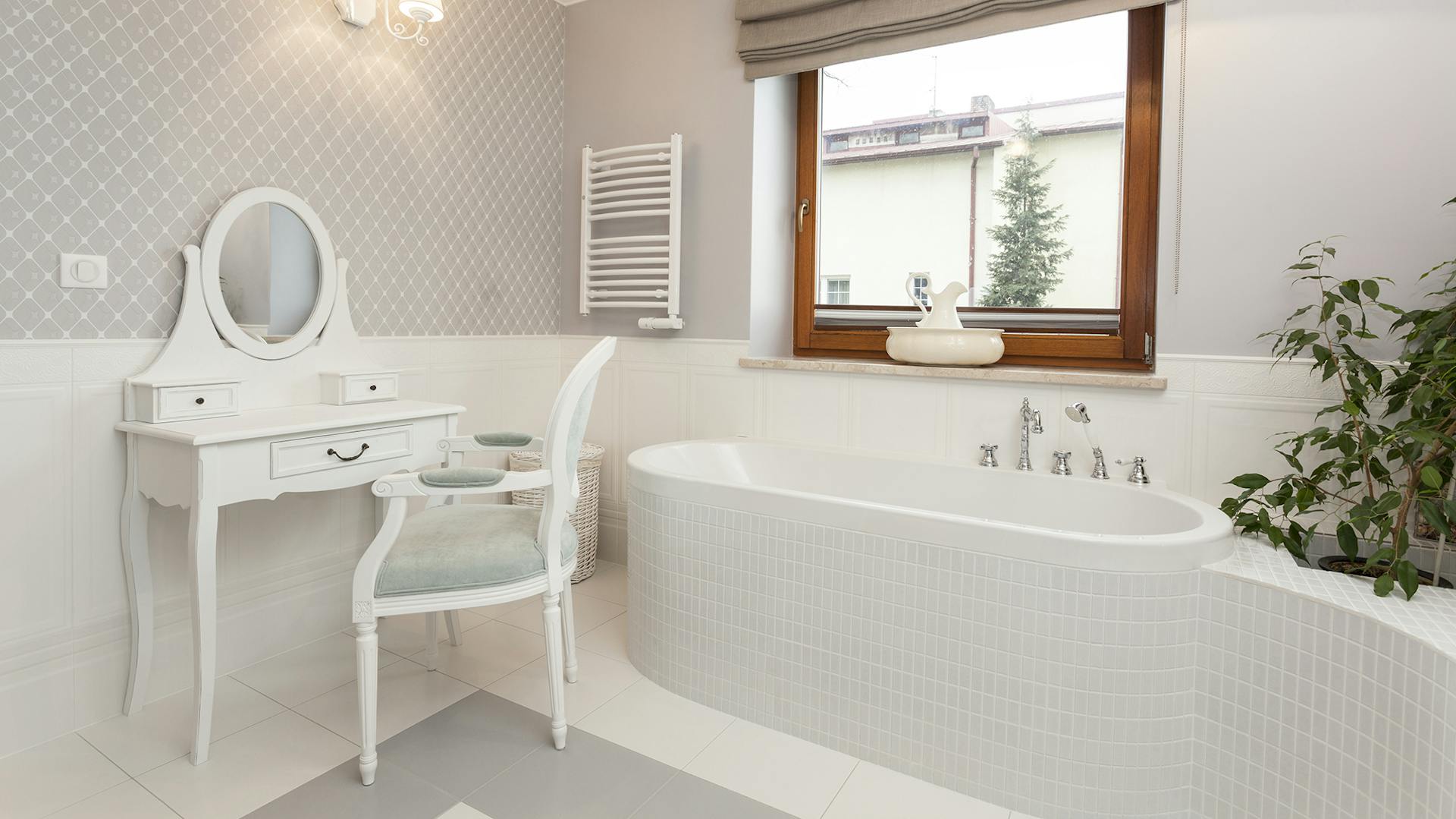 Bagno bianco con vasca piastrellata e tavolo da toeletta bianco con sedia.