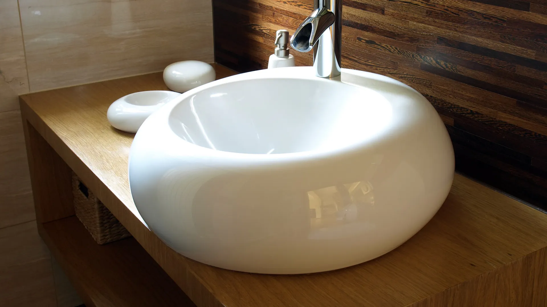Ein weißes Keramikwaschbecken auf einem Waschtisch aus Holz.